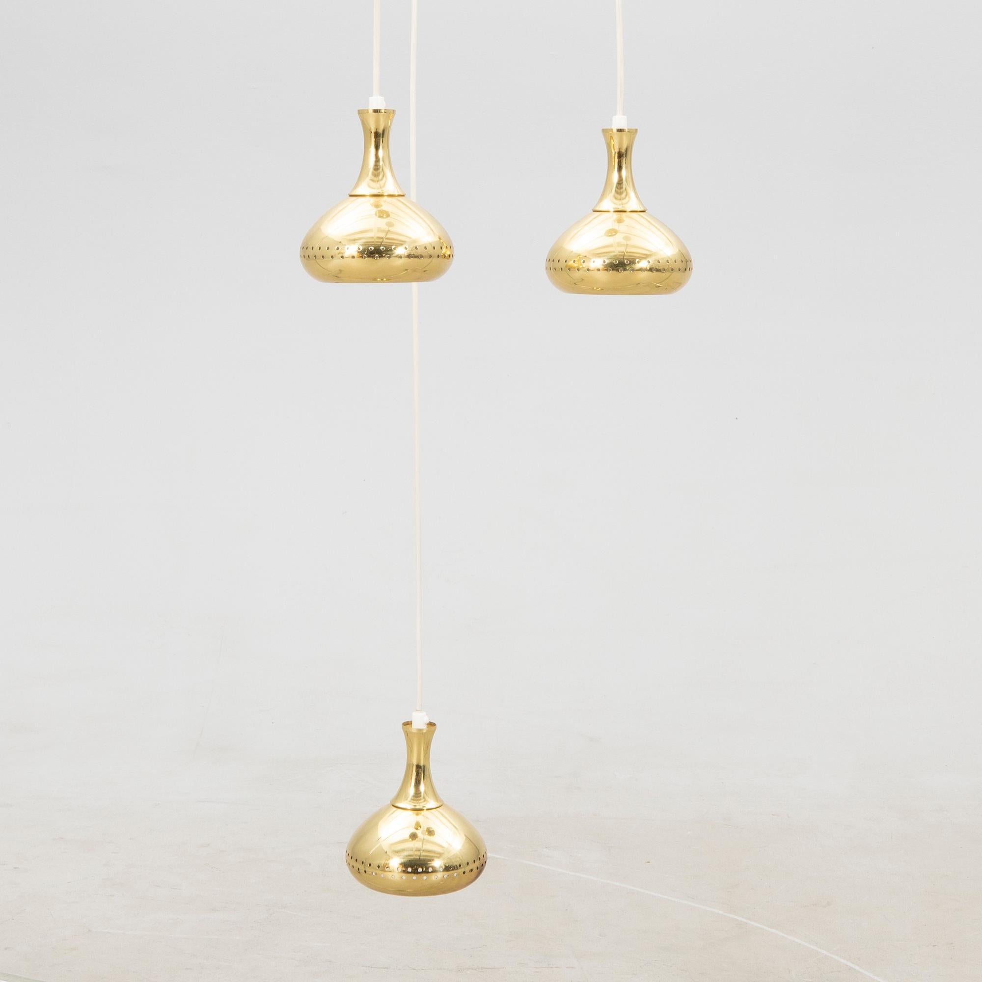 
Hans-Agne Jakobsson  a chandelier with a brass disk holding  3 Pendants lights made by Markaryd in Sweden  around 1960.. 3 lights made of perforated brass with adjustable height 
Good condition 