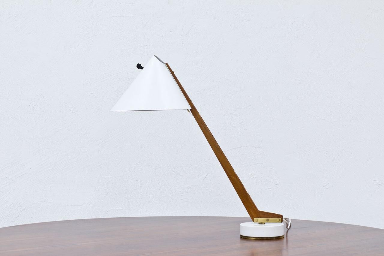 Table lamp model “B – 54? Designed by
Hans-Agne Jakobsson. Manufactured by
his own company at Markaryd, Sweden
during the 1950s. Solid teak stem resting
on a white lacquered metal base with
brass details. White lacquered aluminum
shade with