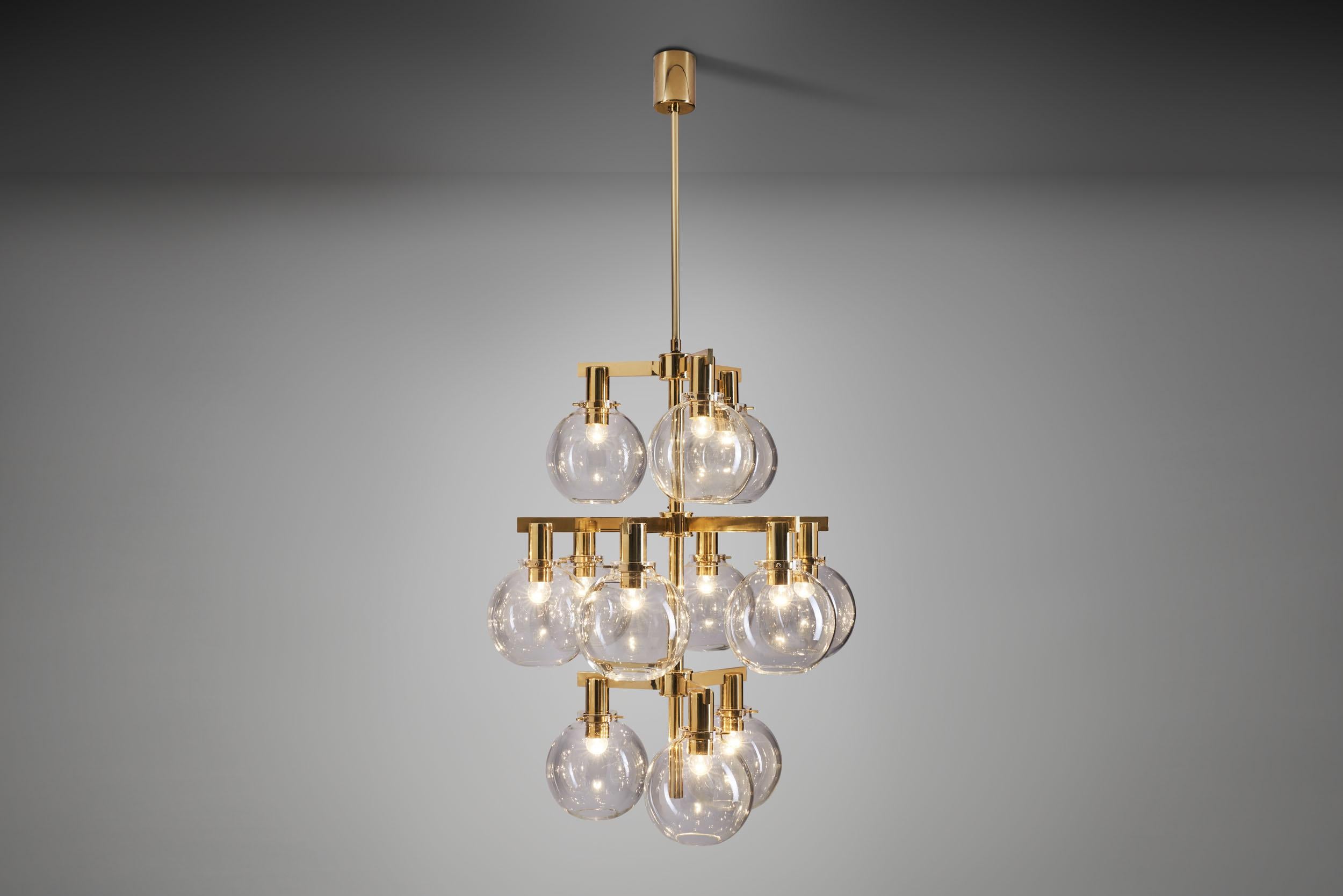 This marvellous pastoral chandelier is among the most recognizable Swedish lighting designs of the mid-century era. With a brass frame holding 12 smoked, translucent glass shades, this model has become synonymous with Hans Agne Jakobsson’s design