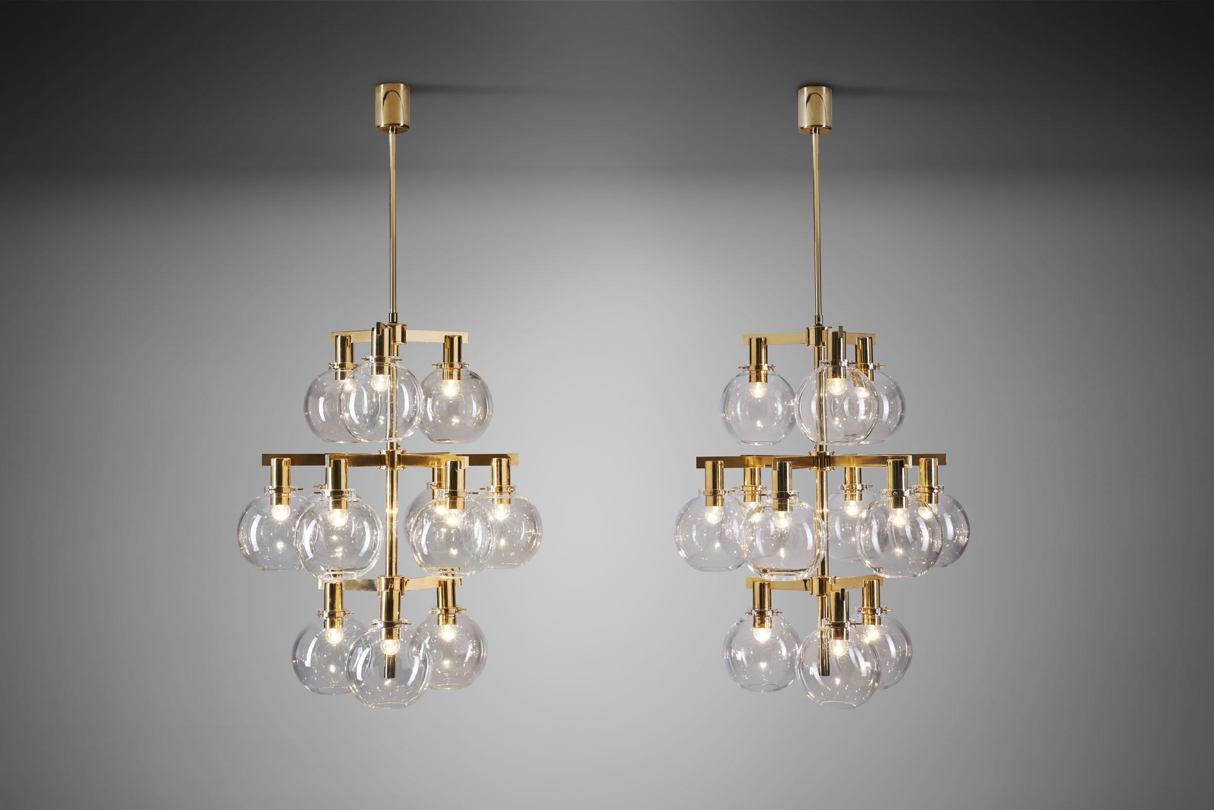 These marvellous pastoral chandeliers are among the most recognizable Swedish lighting designs of the mid-century era. With brass frames holding 12 smoked, translucent glass shades, this model has become synonymous with Hans Agne Jakobsson’s design