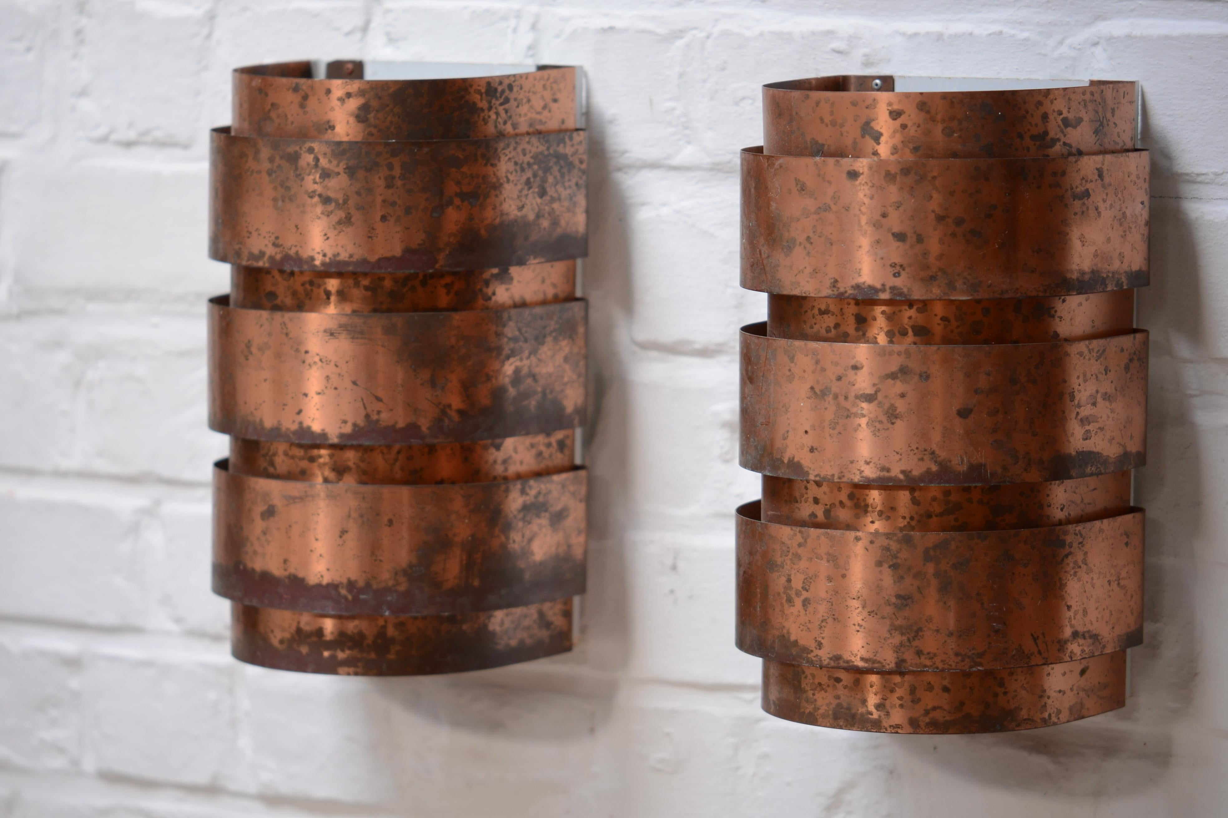 This is a set of 2 wall lamps in patinated copper by Swedish lighting master Hans-Agne Jakobsson. They have a unique patina which is the result of time and use for almost 70 years. Made of copper which is fixed to a white painted steel frame. They