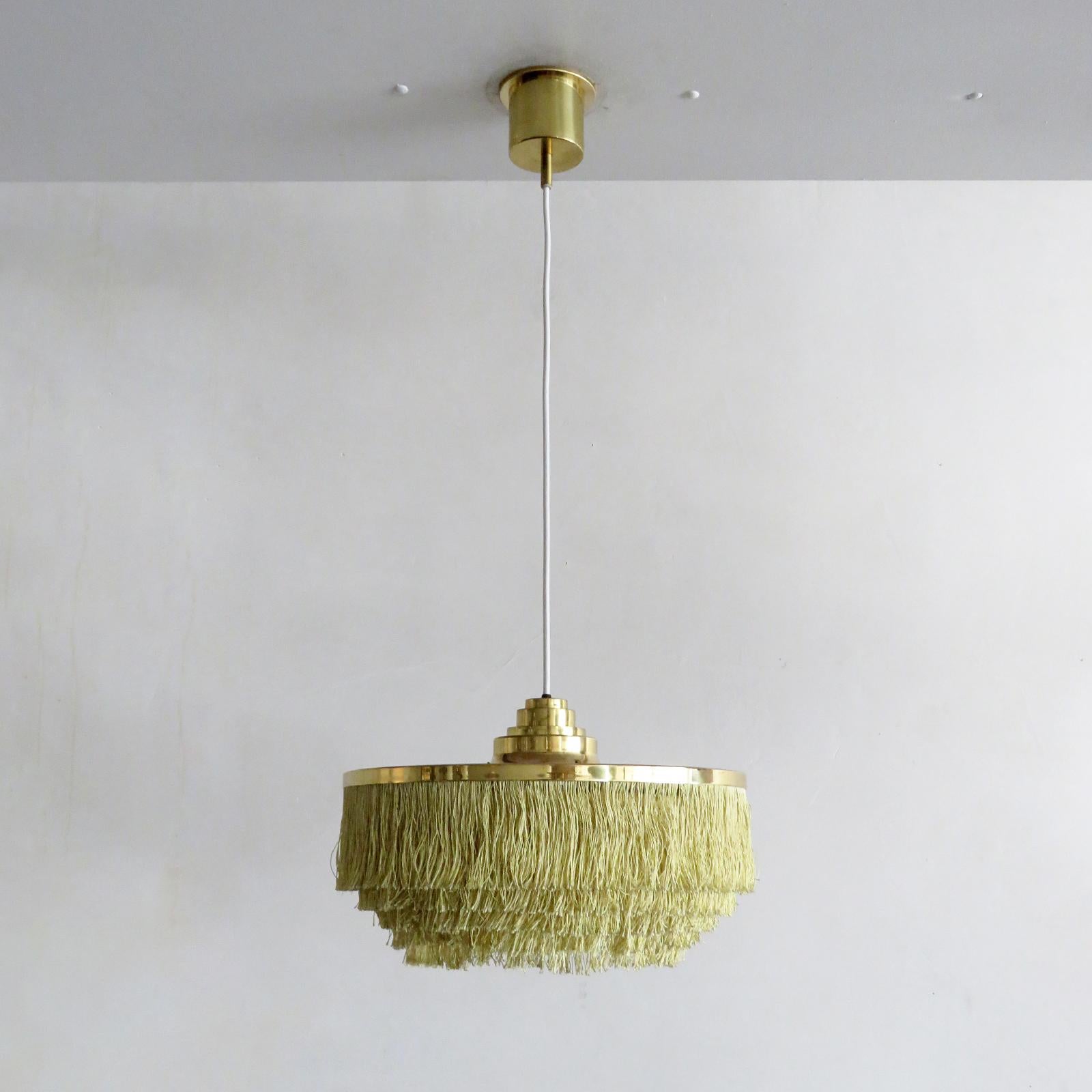 Merveilleuse lampe suspendue de Hans-Agne Jakobsson pour Agnes, Suède, 1960, avec cinq niveaux de cordon de soie à franges jaune/or, cadre en laiton et baldaquin en laiton d'origine. La hauteur totale (montrée à 36