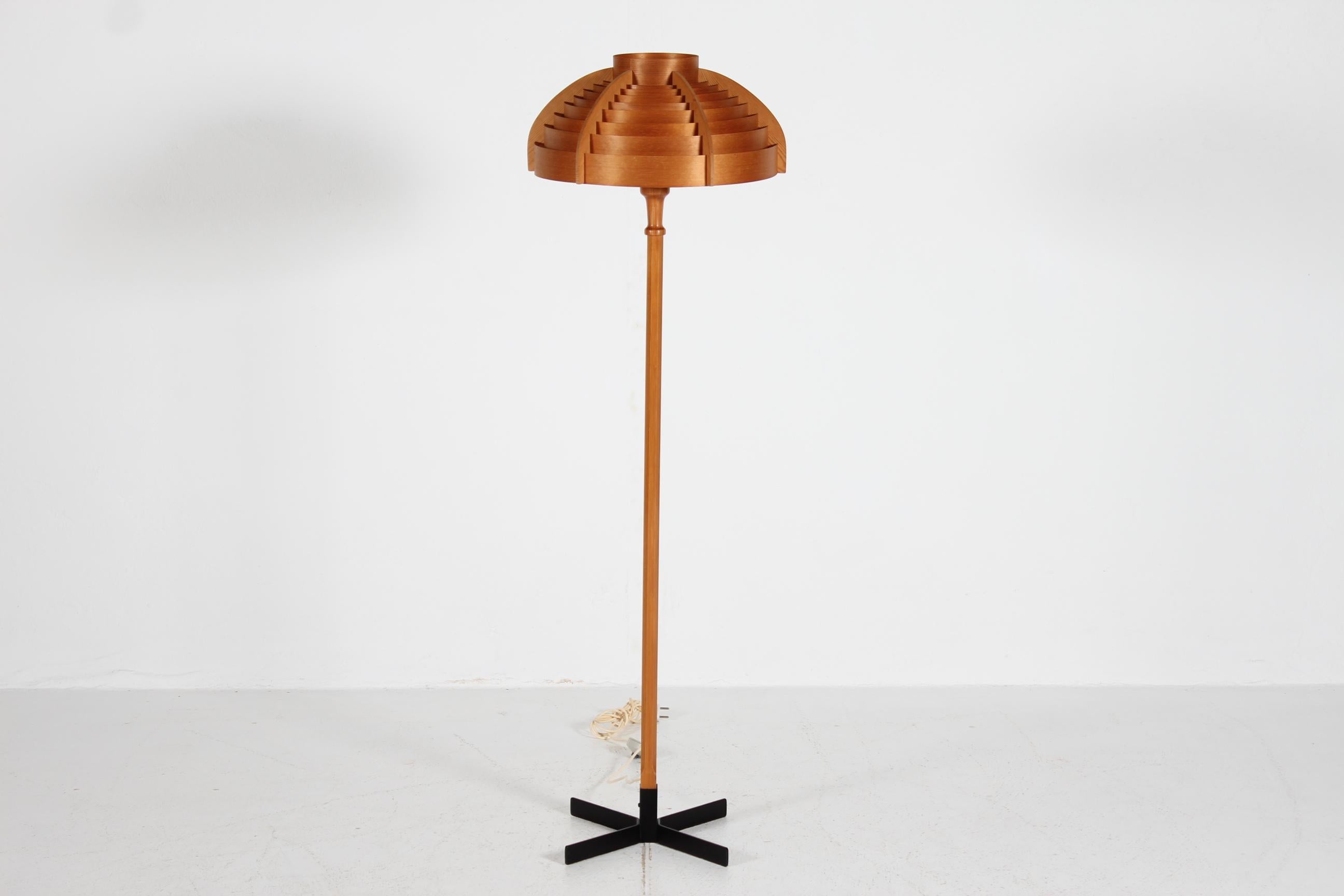 Lampada da terra di Hans-Agne Jakobsson realizzata negli anni '70.
Stelo in legno di pino massiccio montato su una base di metallo laccato nero. 
Il paralume è costruito con trucioli di pino piegati che danno una luce calda e dorata.

Condizioni