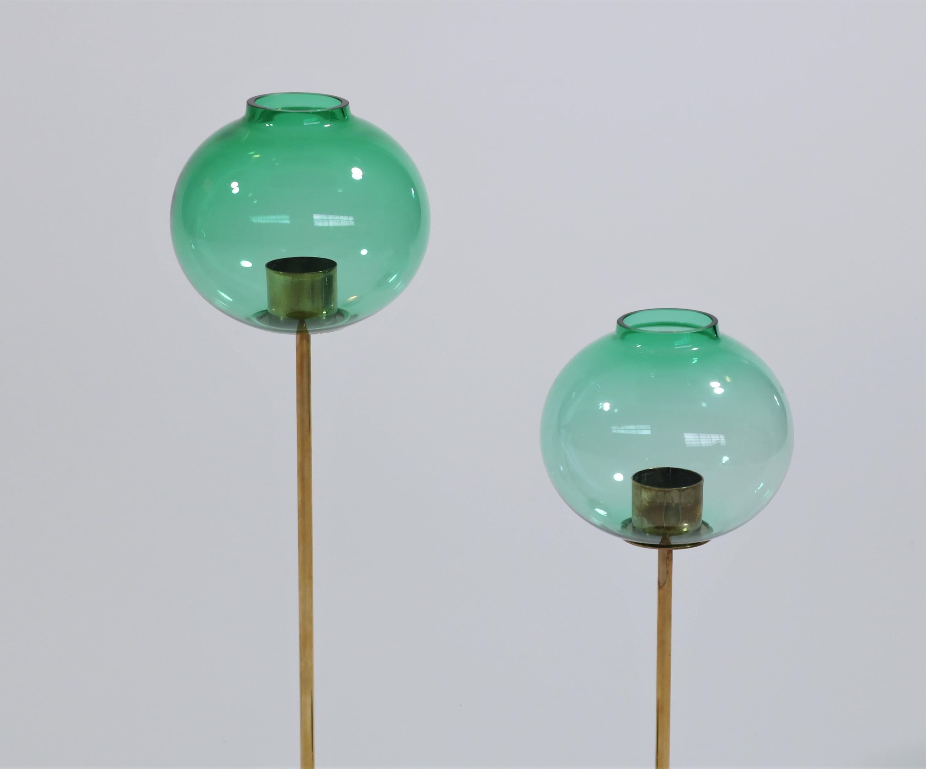 Elegant pair of candlesticks in brass and beautiful turquoise mouth-blown glass by Swedish designer Hans Agne Jakobsson. These candlesticks were manufactured by Swedish company 