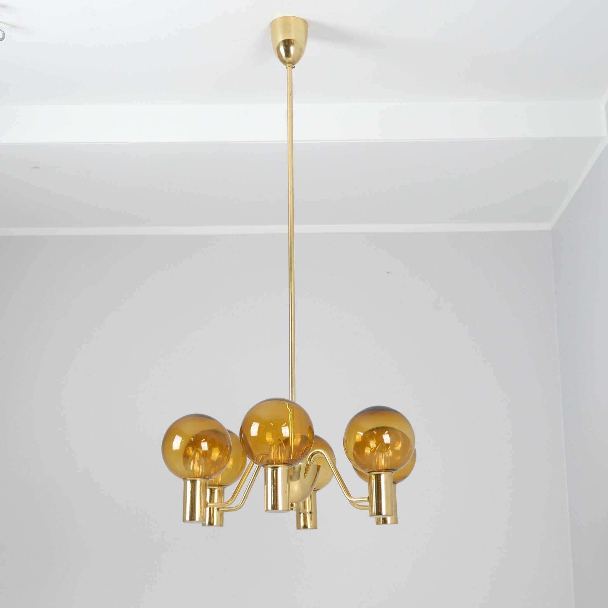 An elegant chandelier by Hans-Agne Jakobsson, exemplifying his iconic design sensibility. This distinctive piece features a sculptural brass structure from which six detachable brown glass shades are suspended. The design is both eye-catching and