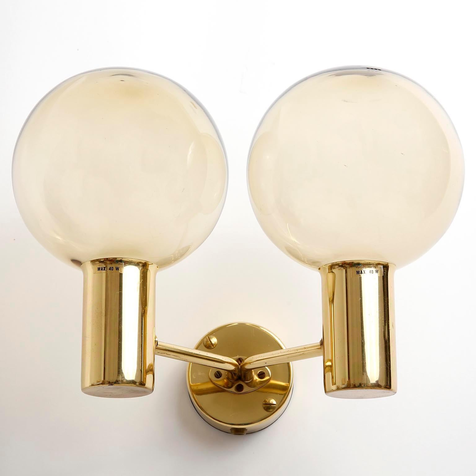 A pair of Scandinavian Modern wall lamps model V 149/2 designed by Hans Agne Jakobsson for AB Markaryd, Sweden, manufactured in midcentury in 1960s.
They are made of a 2-arm polished brass frame which holds two ball shaped amber tone glass lamp
