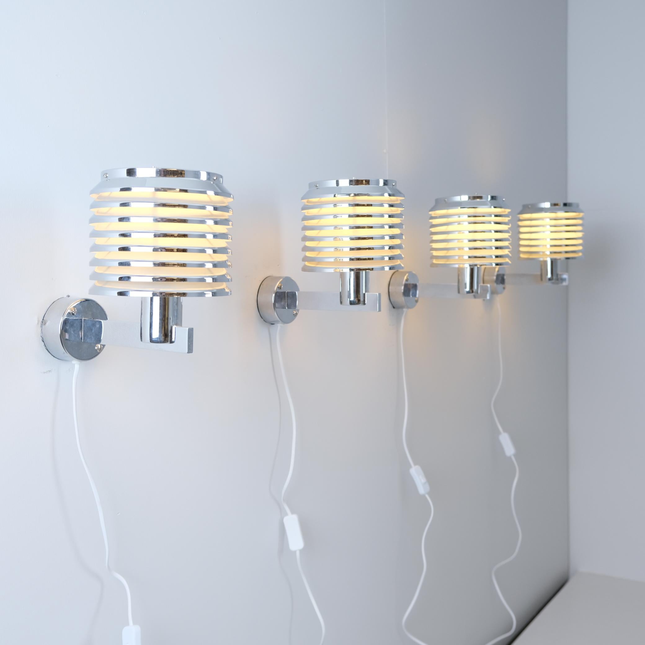 A beautiful set of 4 chrome wall lamps model V-299 designed by Hans-Agne Jakobsson and manufatured by his own company in Markaryd Sweden in the 1950s. The lamps feature a full chrome frame with a layered shade casting a warm light evenly into the