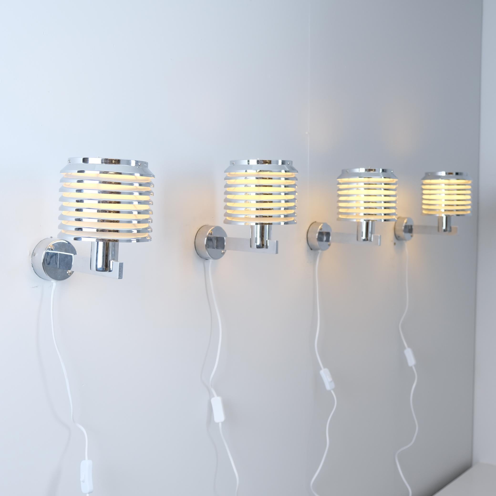 A beautiful set of 4 chrome wall lamps model V-299 designed by Hans-Agne Jakobsson and manufactured by his own company in Markaryd Sweden in the 1950s. The lamps feature a full chrome frame with a layered shade casting a warm light evenly into the
