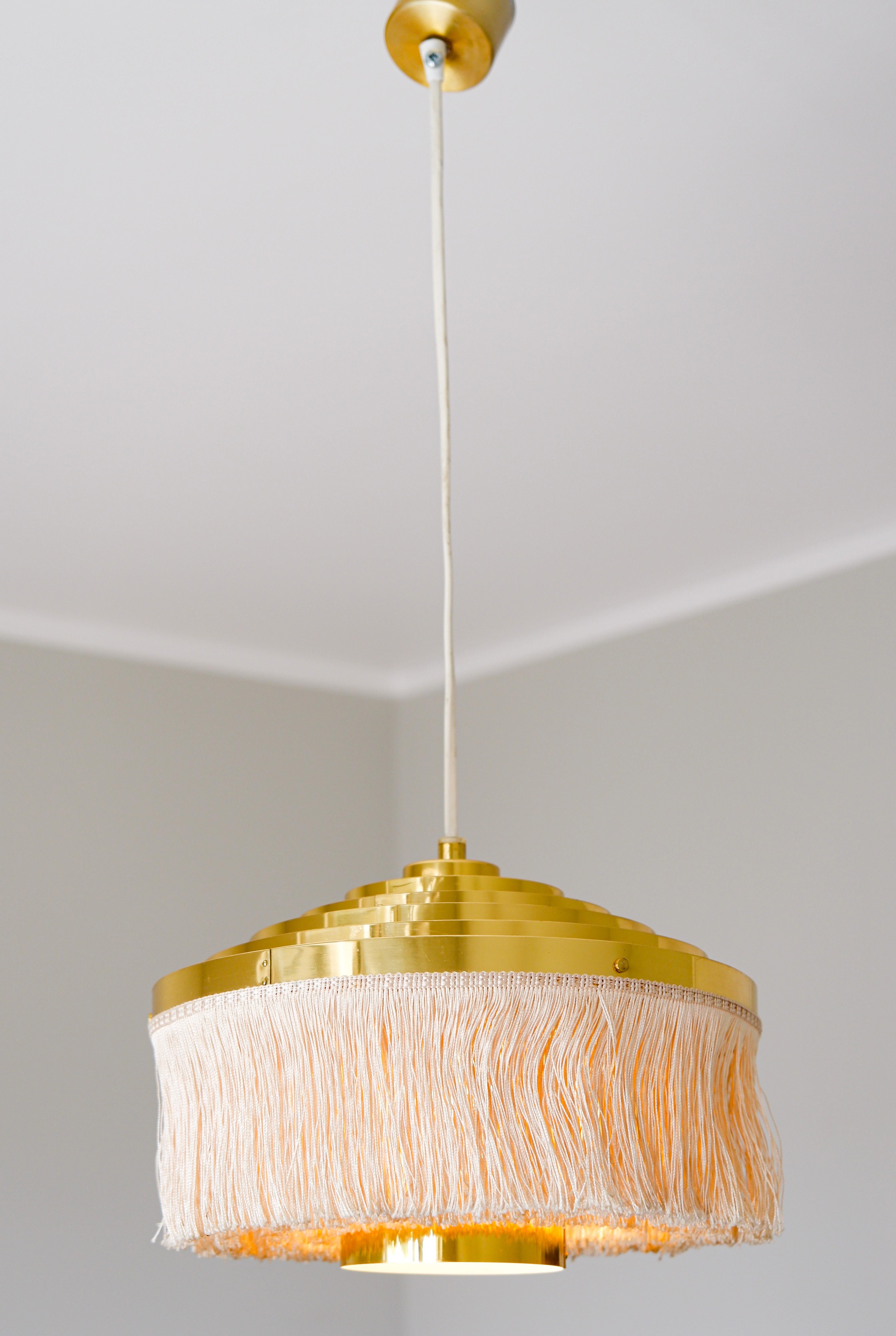 Lampada con frange in seta e ottone di Hans Agne Jakobsson. La lampada è realizzata con anelli di ottone e frange di seta. Buone condizioni vintage. Hans-Agne Jakobsson è uno dei designer scandinavi più influenti dell'ultima parte del secolo,