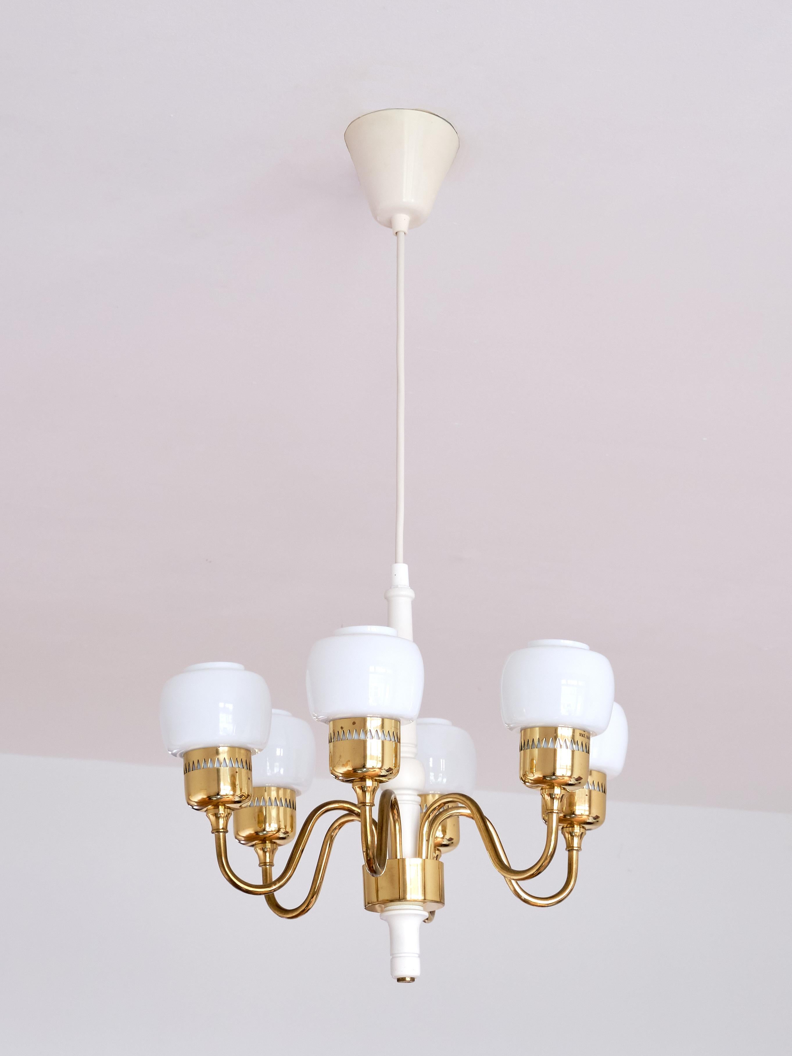 This elegant chandelier was designed by Hans-Agne Jakobsson and produced by his company in Markaryd, Sweden in the 1960s. This particular model is number T-526. The lamp consists of a brass ring with six arms and shade holders in brass as well. The
