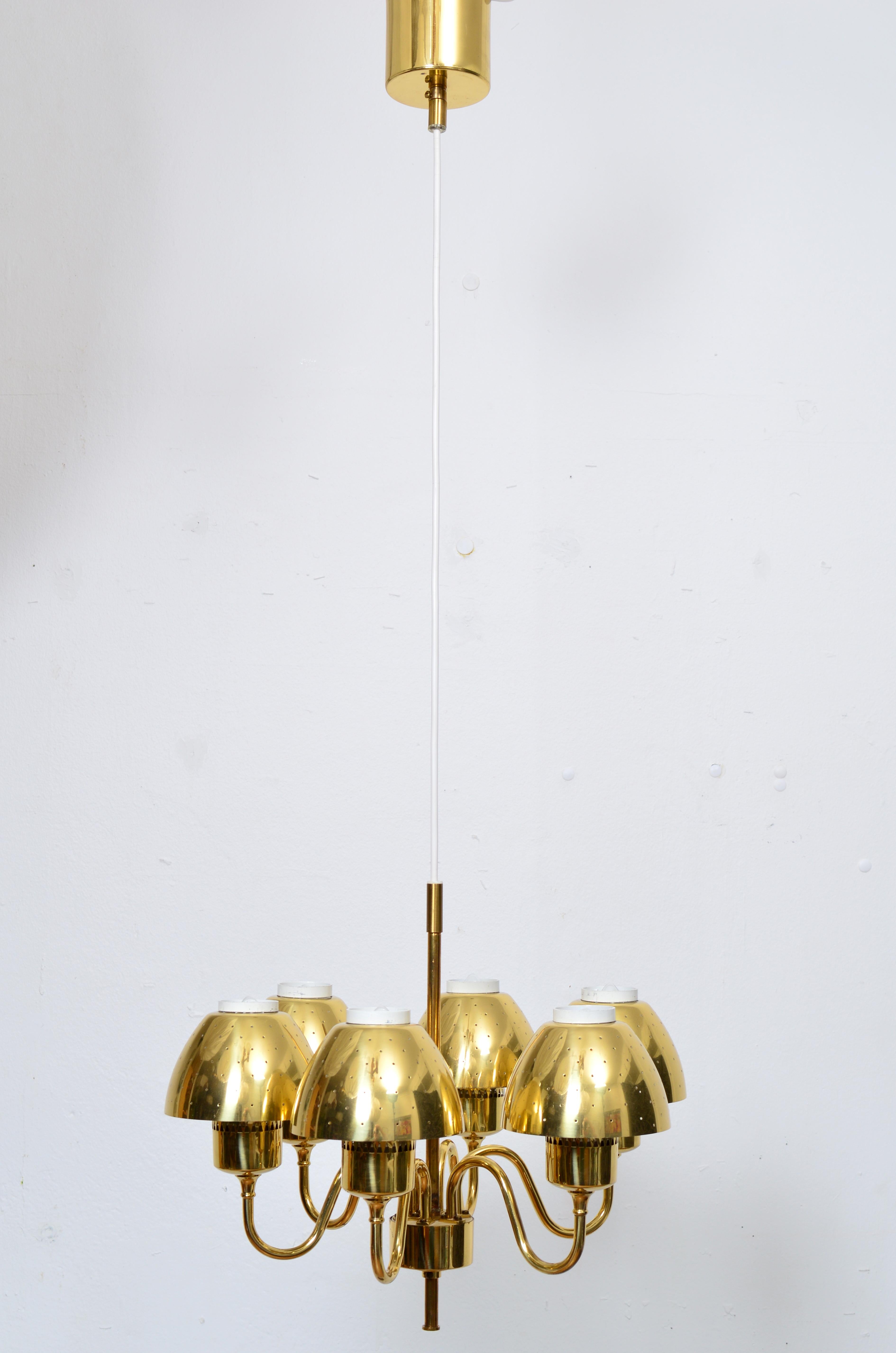 This elegant  pendant / chandelier was designed by Hans-Agne Jakobsson and produced by his company in Markaryd, Sweden in the 1960s. This particular model is number T-526. The lamp consists of a brass ring with six arms, six perforated shades and