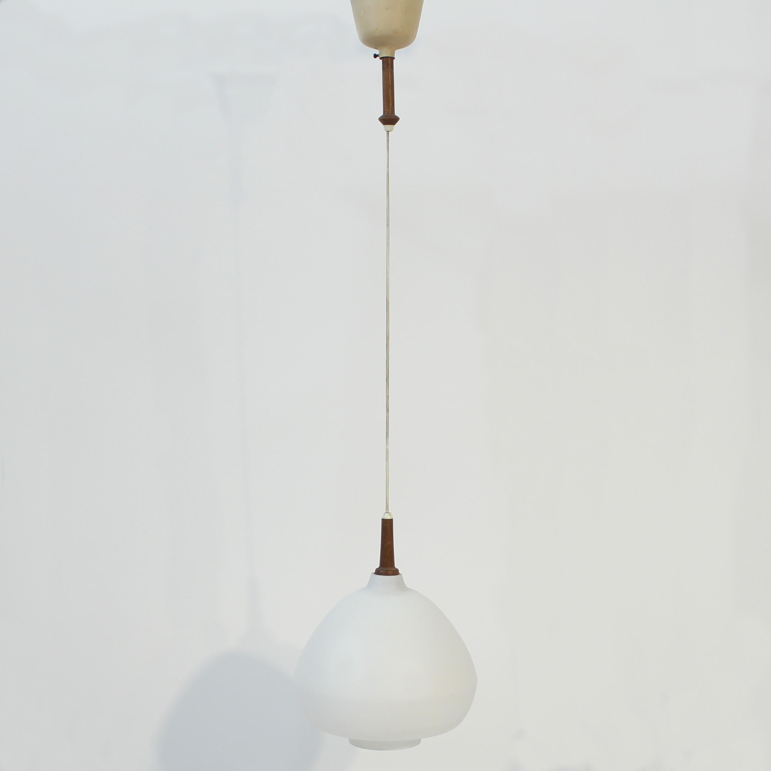 Ceiling lamp in teak and opaline glass designed by Hans-Agne Jakobsson for his own company in the early part of his career in the 1950s. It consists of an opaline glass, dome shaped, shade with a few teak details and a metal ceiling cup. Marked with