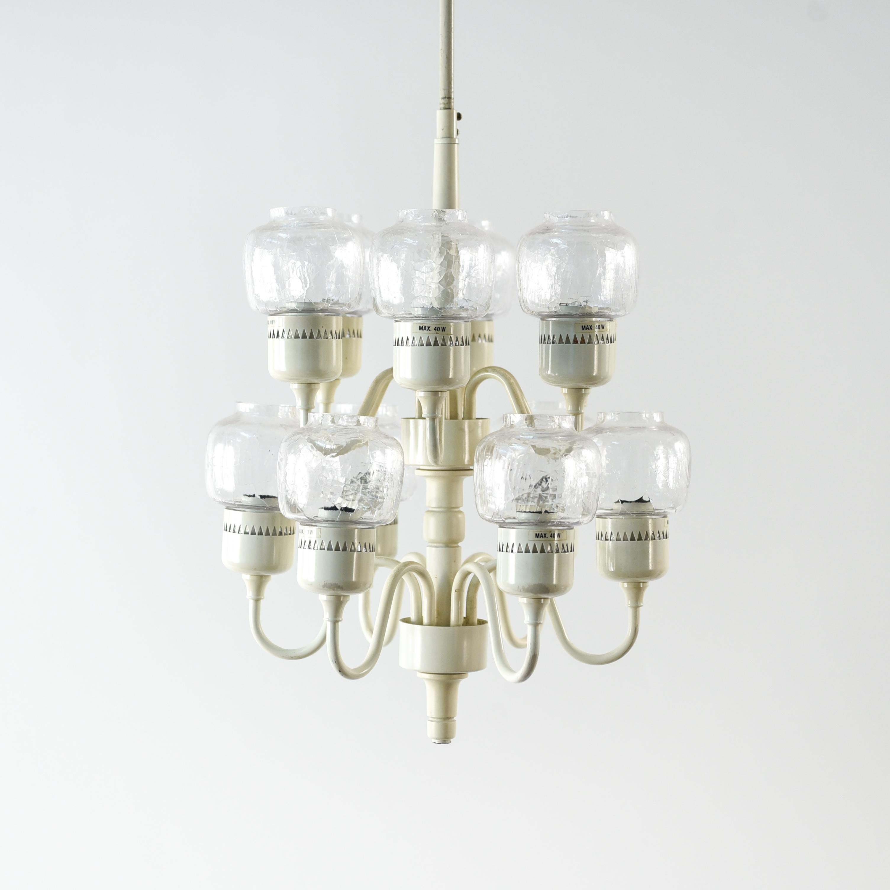 This is a rare chandelier designed by Hans Agne Jakobsson and produced by Markaryd, Sweden. This two-tier chandelier has an off-white lacquered body with twelve lights. Each light has its own clear glass hurricane shade.