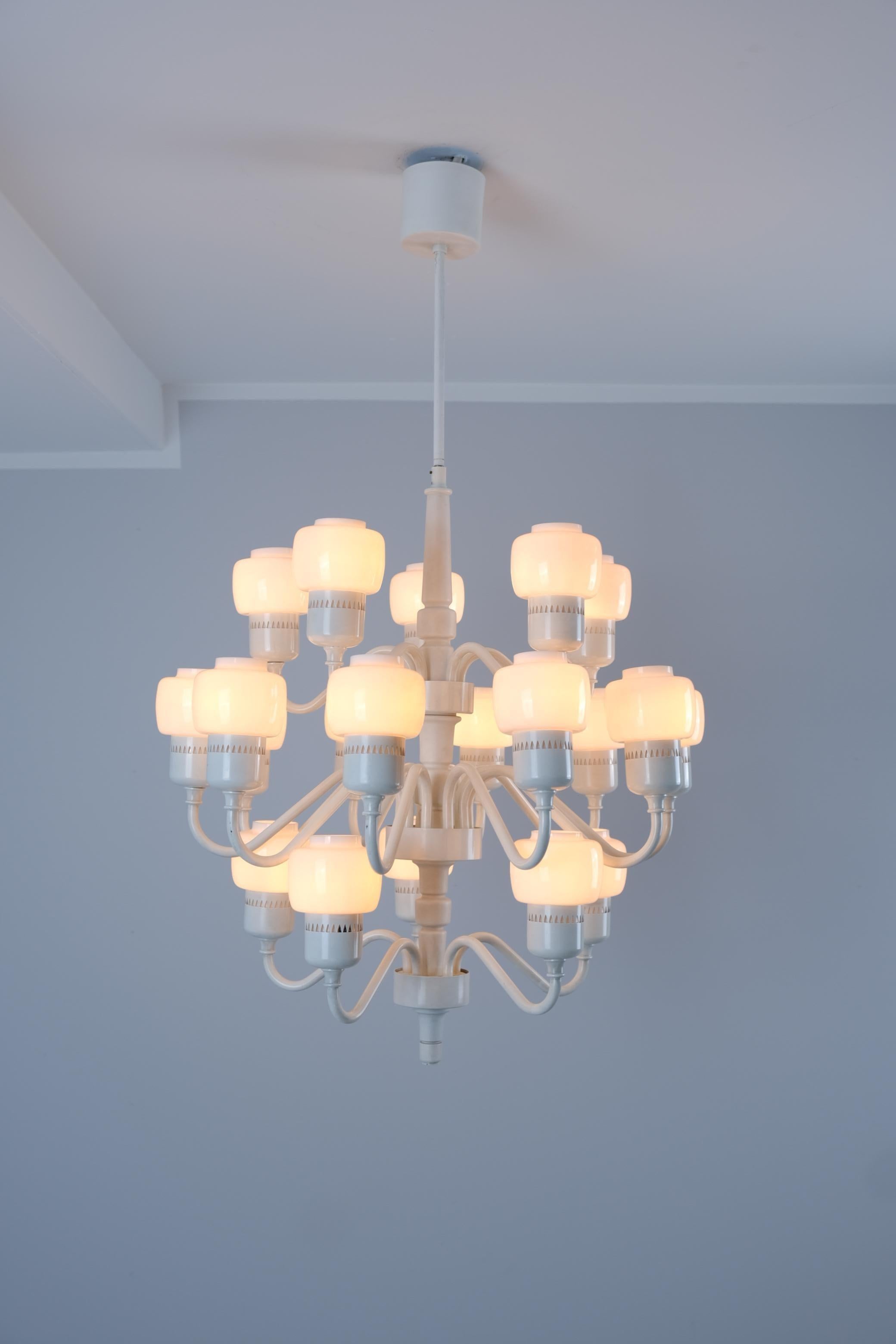 Uno splendido lampadario a venti bracci completamente bianco, realizzato dall'importante designer svedese Hans-Agne Jakobsson. La lampada è composta da una parte centrale in legno verniciato bianco con venti bracci in metallo che sporgono su tre