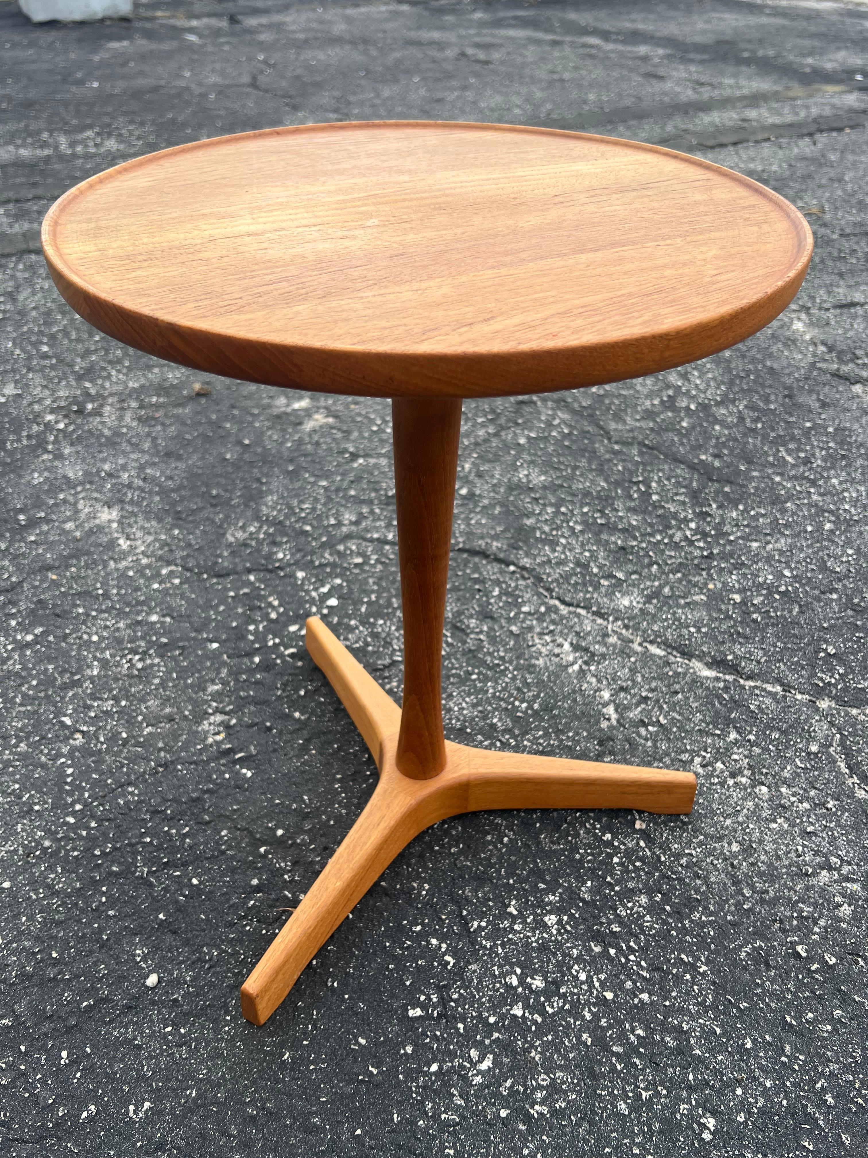 A classic Danish side table with three legs by Hans Andersen. Round top in original  teak wood. Nice teak grain and very good condition. Signed underneath.