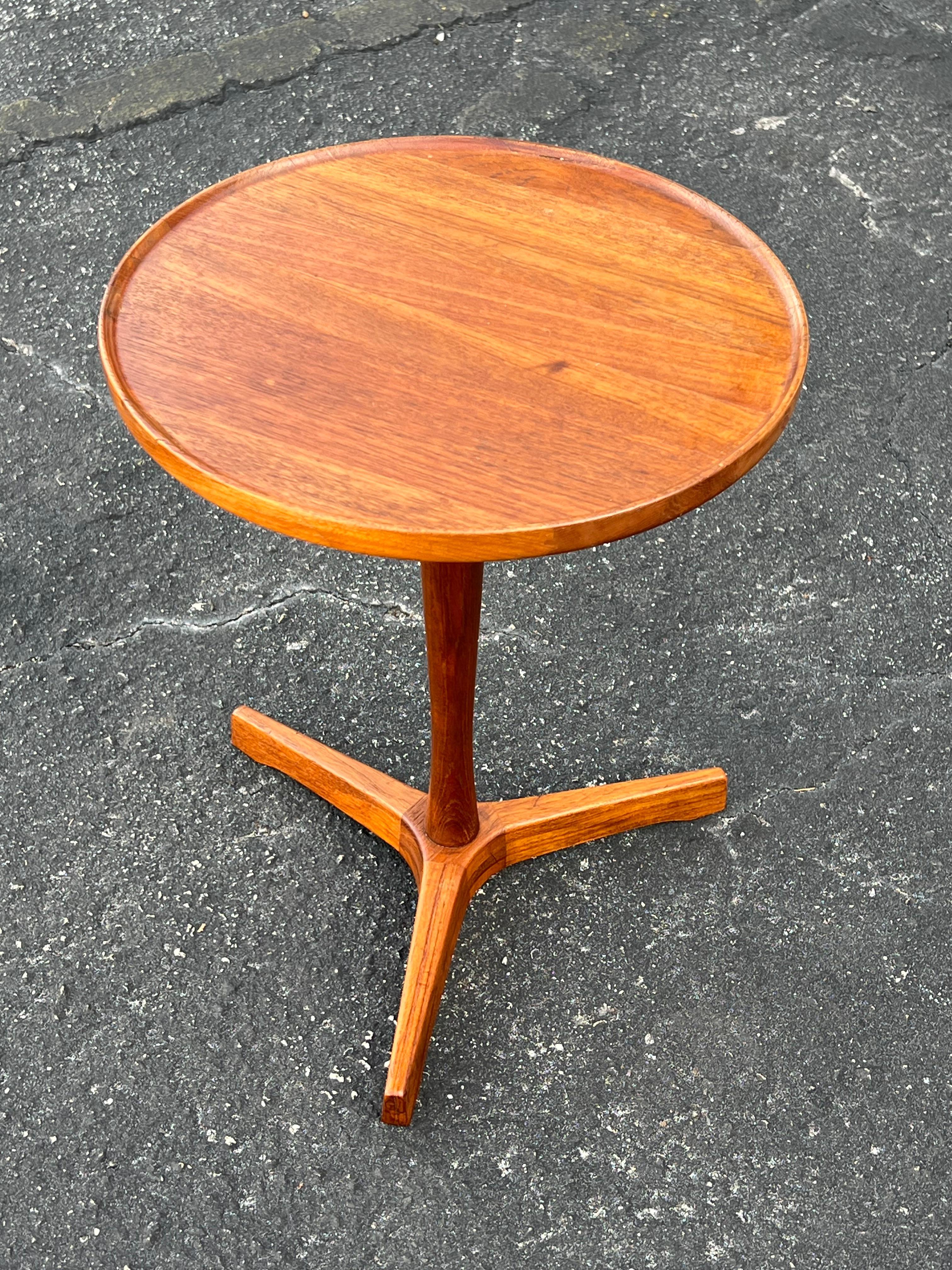 A classic Danish side table with three legs by Hans Andersen. Round top in original  teak wood. Nice patina and very good condition. Signed underneath.