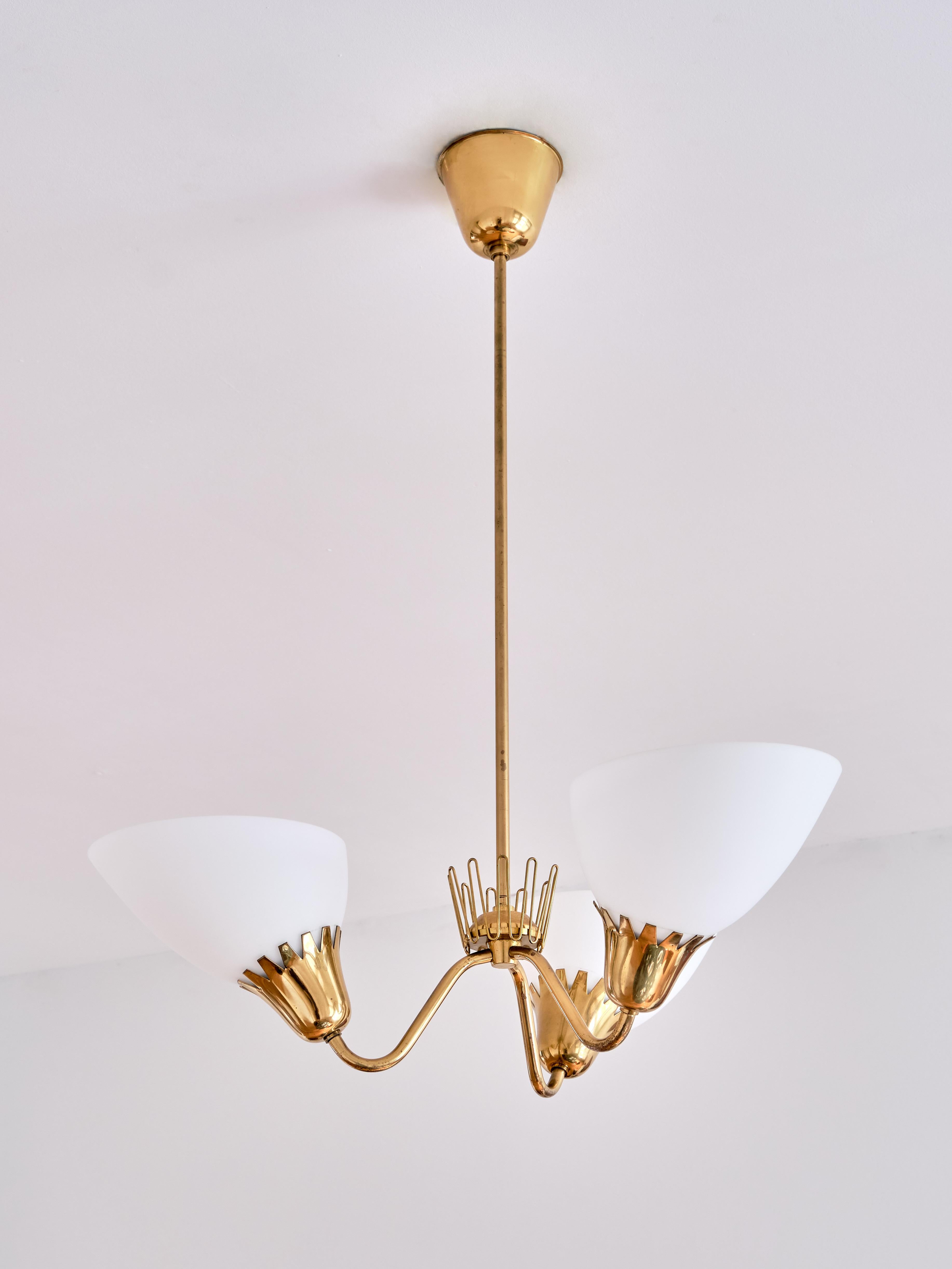 This rare three arm chandelier was produced by ASEA in Sweden in the early 1950s. Brass stem, three arms and fittings with matte opaline glass shades. The zigzag edges of the fittings and the decorative brass crown detail in the middle are