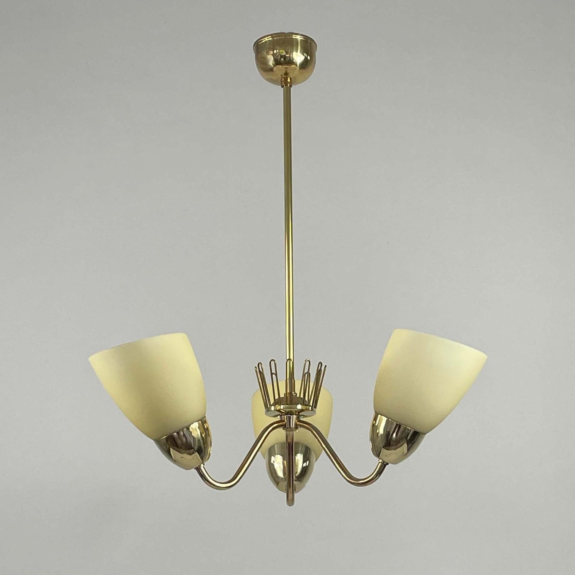 This three light Scandinavian Modern chandelier was designed by Hans Bergström and manufactured by ASEA in Sweden in the early 1950s. 

The fixture features three cream colored opaline frosted glass lampshades which diffuse the light softly and