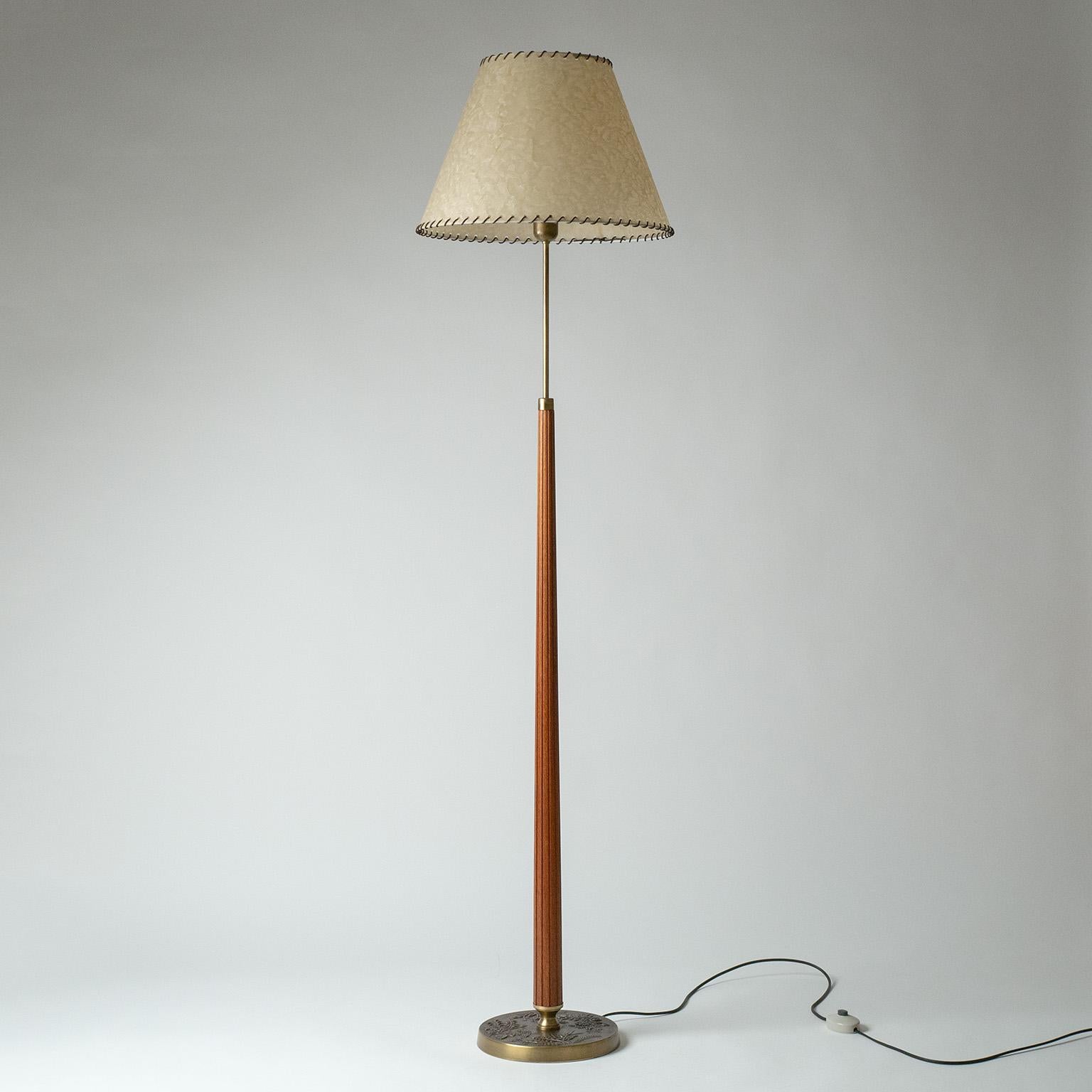 Brass and teak floor lamp by Hans Bergström for ASEA Belysning from the 1950s. Cast brass base with beautiful floral decorations and a tapered fluted teak stem. The large shade has parchment paper covering with leather trimming. Very nice condition
