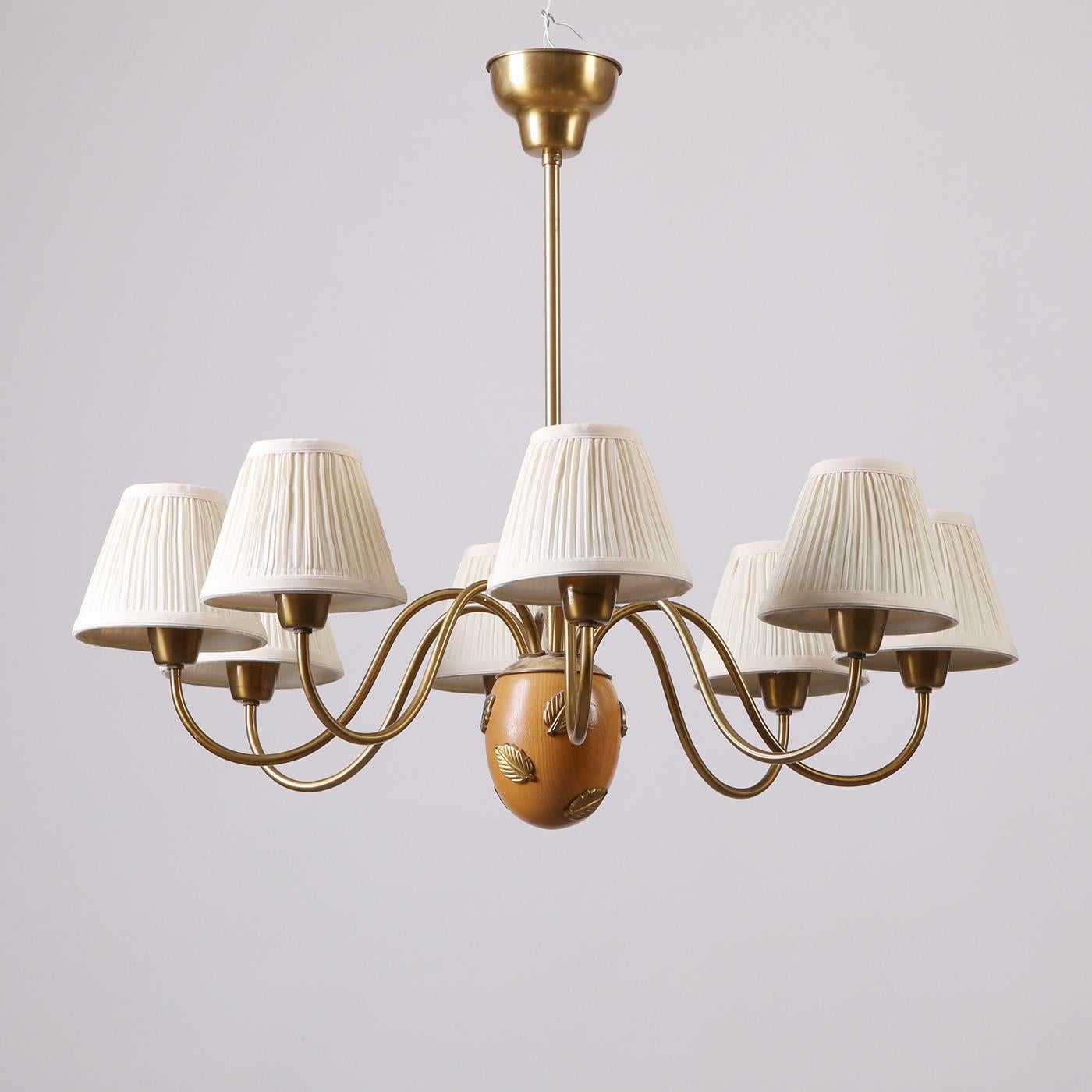 A remarkable 8-arm chandelier (model '10/8'), designed by Hans Bergström. Produced by Ateljé Lyktan in the 1940s. Made from brass, details in wood, the chandelier features new lampshades. Manufacturer's label to the brass arm.

Designed by Swedish
