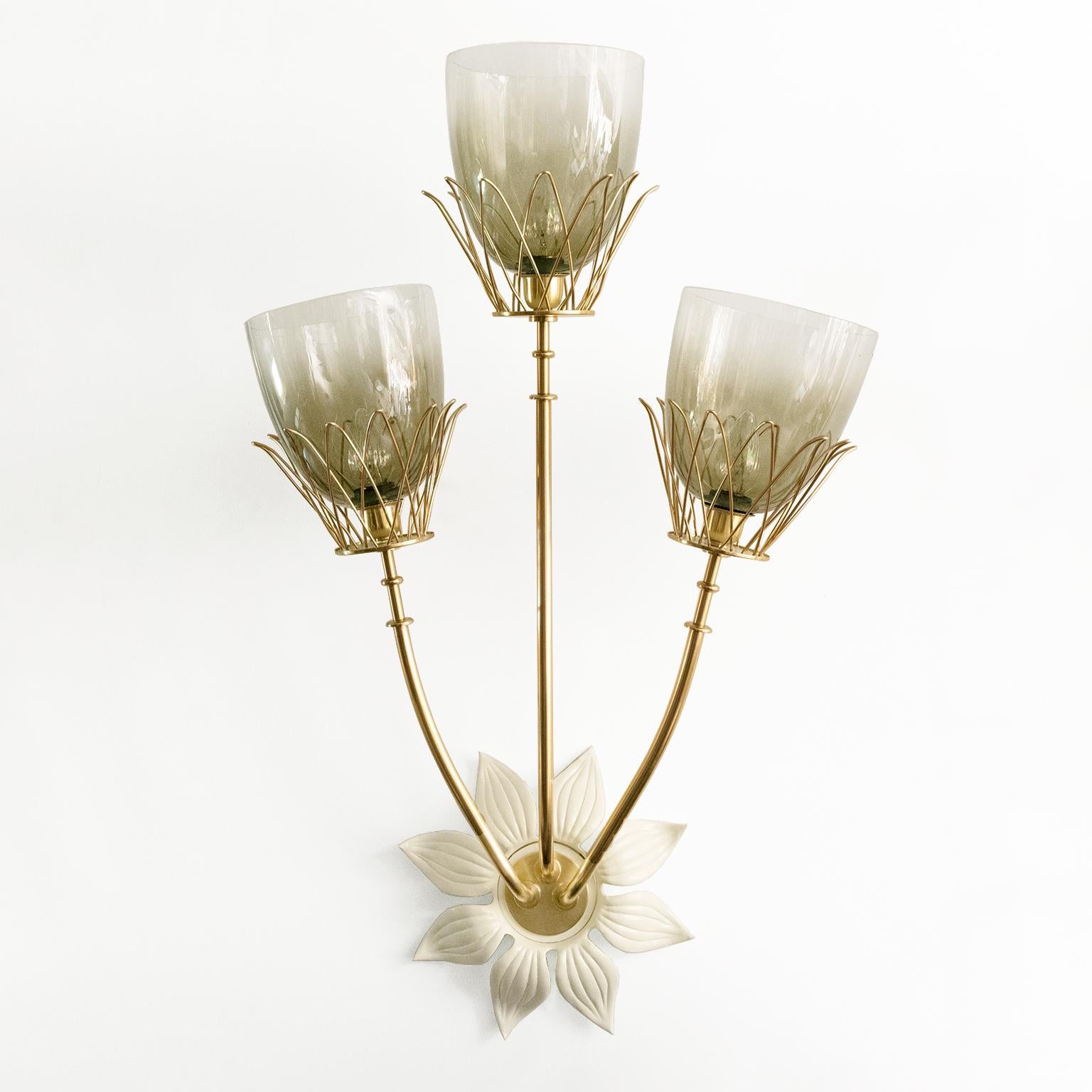 Large Hans Bergstrom, Scandinavian Modern 3-arm sconce in brass with lacquered metal backplate in the form of a flower. Each arm ends with a brass wire petal form shade holder. These shades are replacements. The sconce has been newly polished and