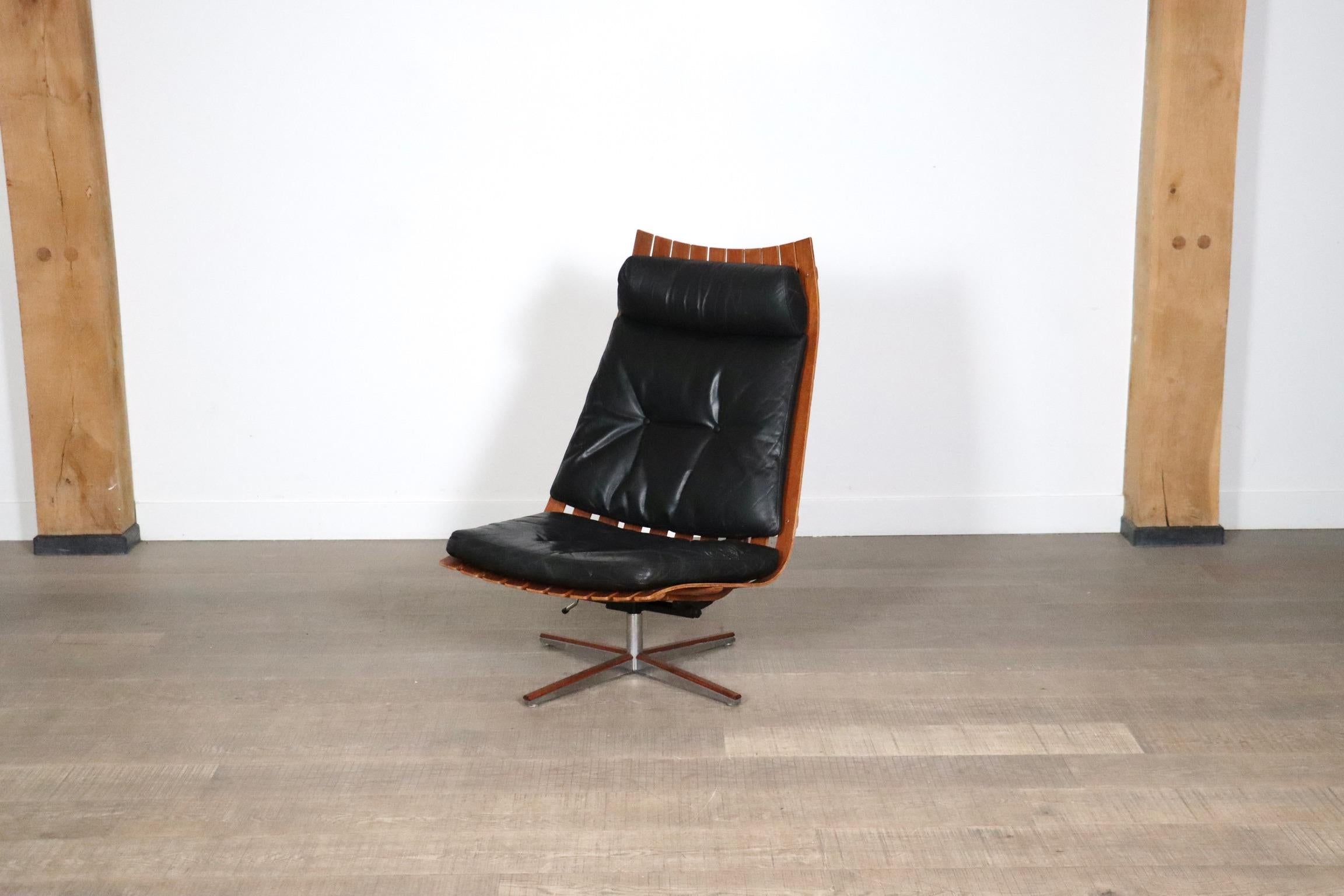 Magnifique chaise longue pivotante à haut dossier modèle Scandia, conçue par Hans Brattrud pour Hove Mobler, Norvège 1957.
Entièrement d'origine, les coussins en cuir noir sont légèrement patinés, ce qui confère à la chaise une belle allure