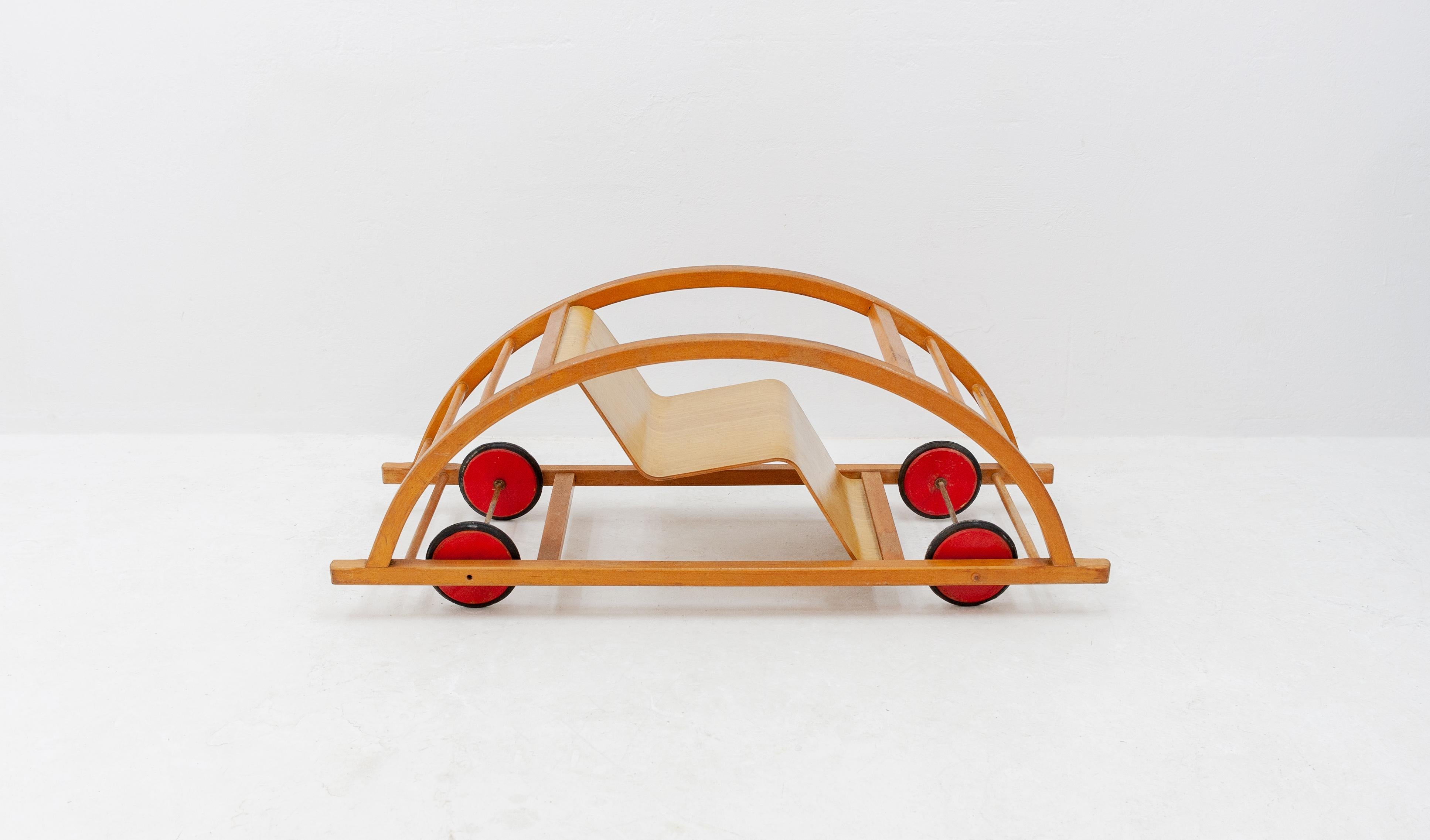 A beautiful and completely original Schaukelwagen with beech plywood seat from 1950 designed by Hans Brockhage and Erwin Andrä under supervision of the Dutch Mart Stam. This vintage walking car can serve as a seesaw when flipped over and is in