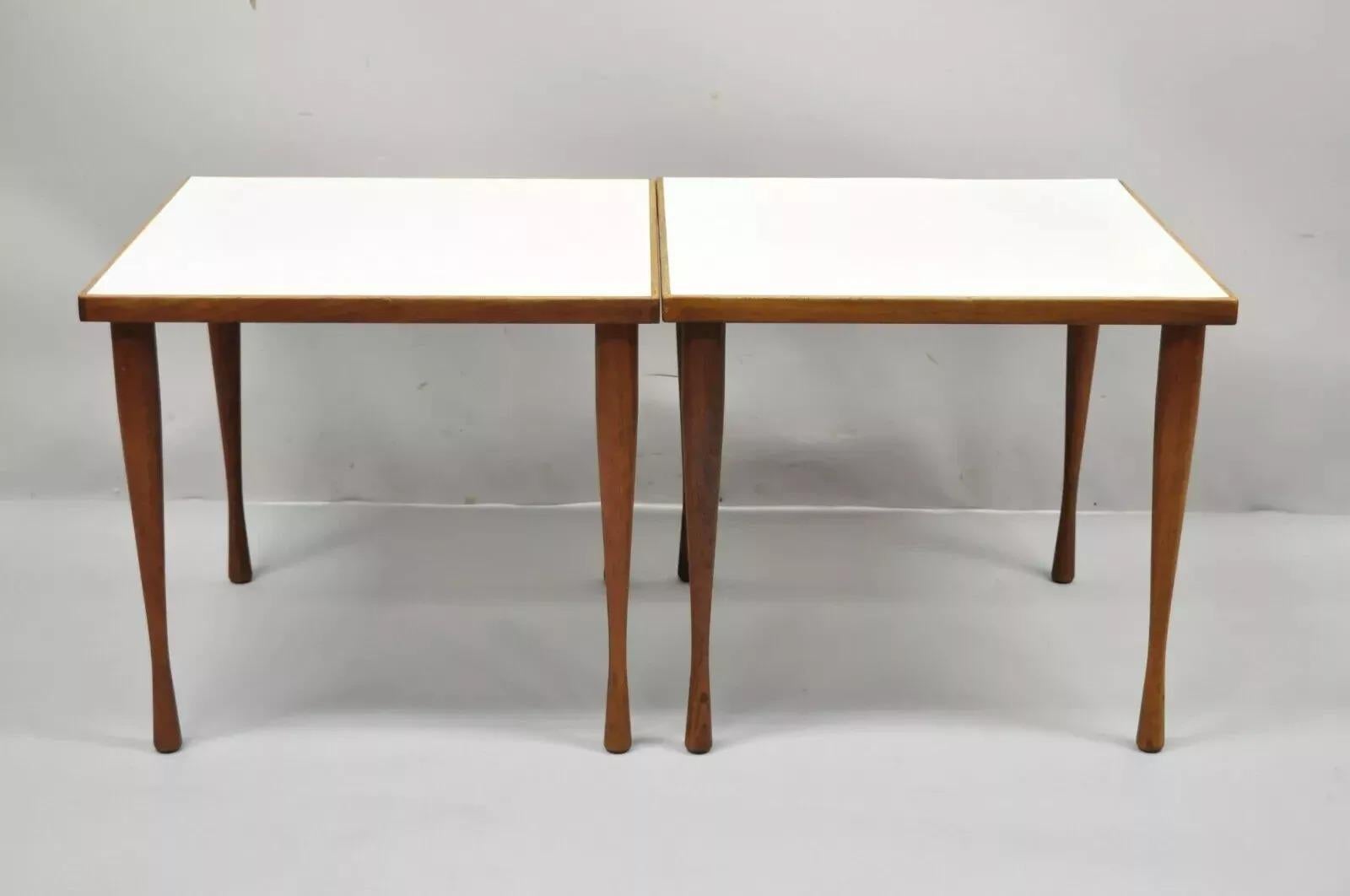 Vintage Hans C Andersen Danish Mid Century Modern Teak & Formica Snack Side Tables - Pair. Item features hour glass teak wood tapered legs, white formica top, original label, and clean modernist lines. Circa Mid 20th Century. Measurements: 16