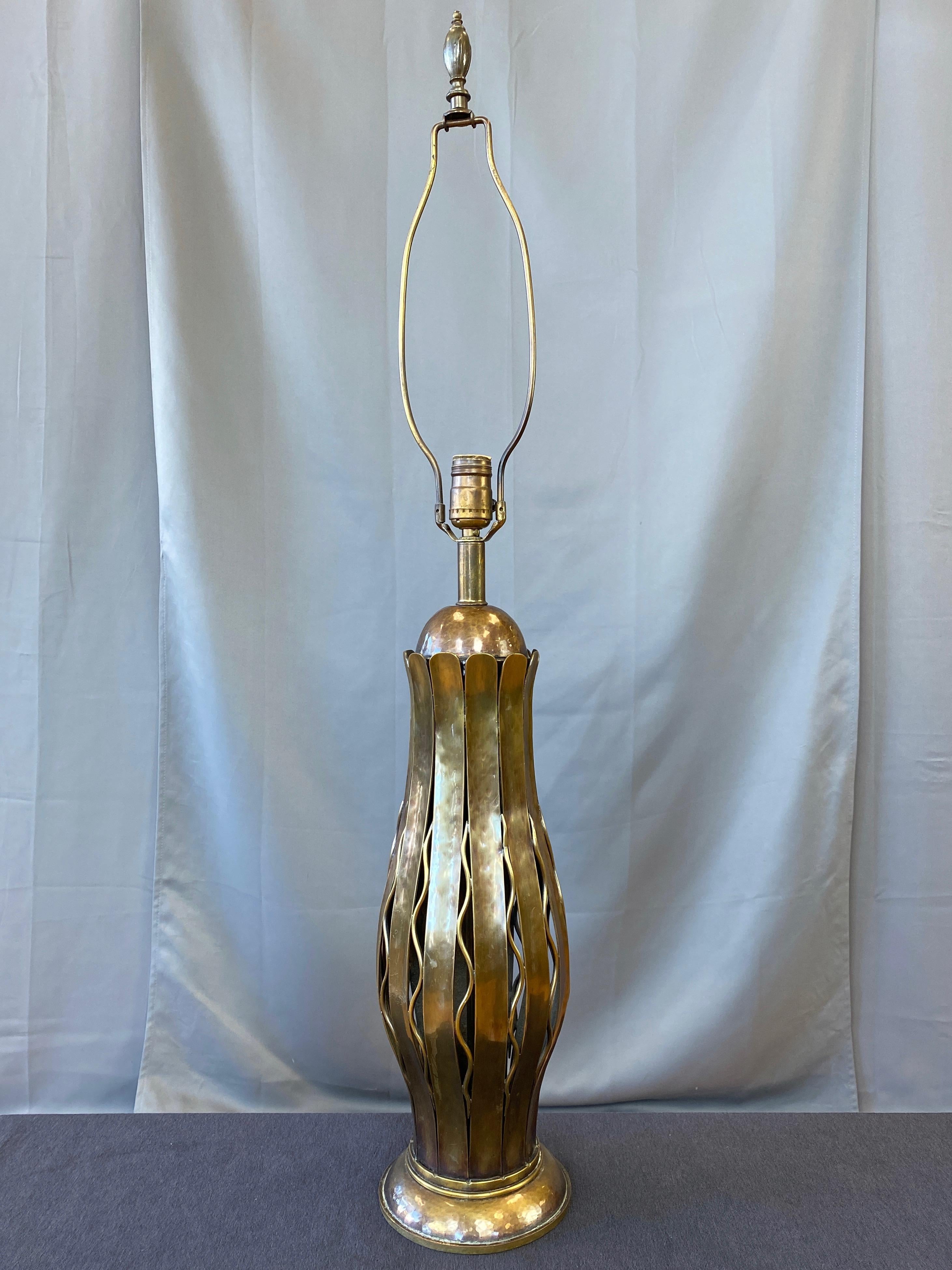 Lampe de table haute en cuivre et laiton martelé, très rare, datant des années 1950, fabriquée exclusivement par Hans Grag pour Gump's de San Francisco.

Le capuchon en demi-dôme en cuivre habilement formé et martelé à la main et les douves en