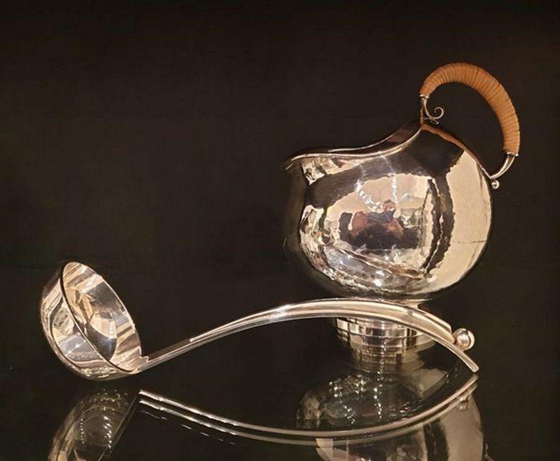 Gravy boat and spoon designed by Karl Gustav Hansen in 1933/ 1934. Executed in 1949 by Hans Hansen silver factory, Kolding, Denmark. Sterling silver with wicker handle. Hallmarked.
Measures: Height: 5.83 in ( 14,8 cm ), width: 4.33 in ( 11 cm ),