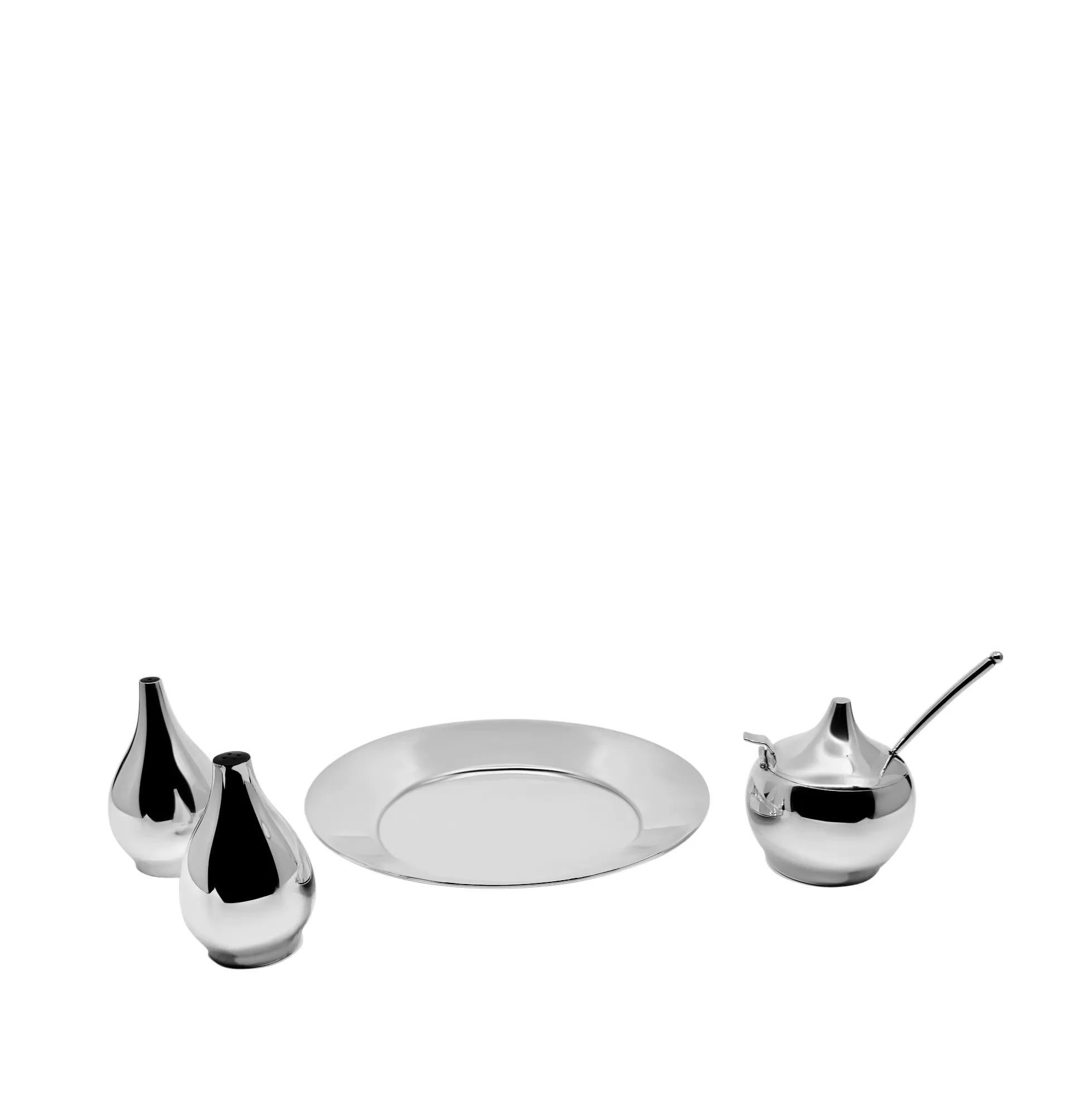 Una vinagrera vintage de plata de ley de Hans Hansen, fabricada en 1963. El juego se compone de una bandeja redonda con borde en relieve, junto a saleros y pimenteros en forma de lágrima con tamices de baquelita. El tarro de mostaza, con tapa