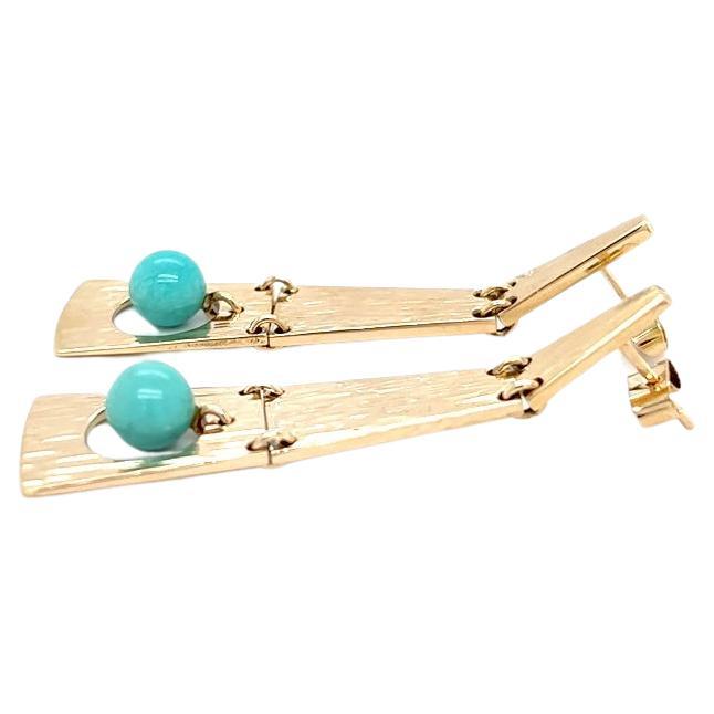 One pair of 14 karat yellow gold pendant design earring by Danish designer Hans Hansen, set with one 6.90mm round turquoise bead. The earrings measure just over two (2) inches long and are complete with friction posts and backs. The earrings are