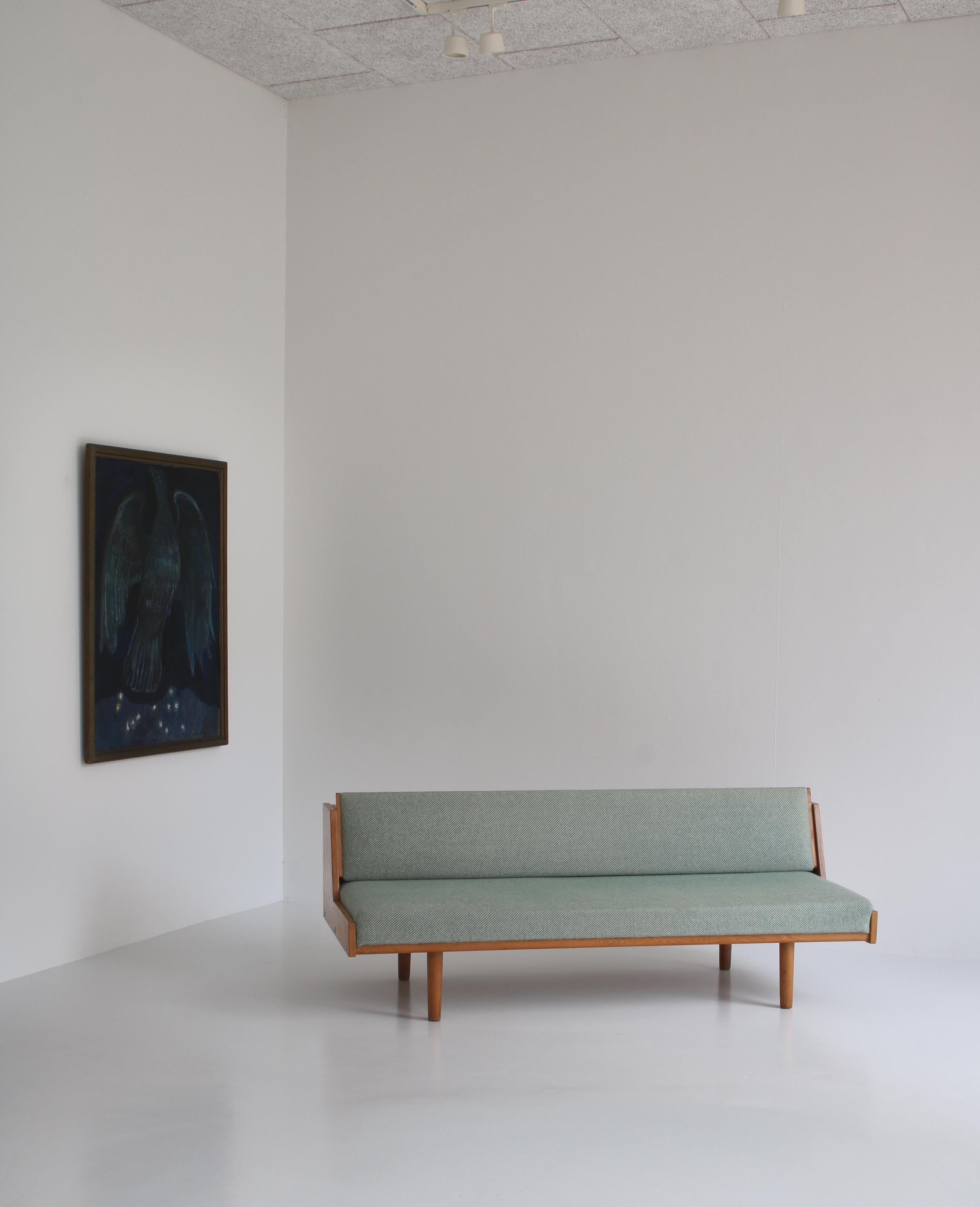 Designed by Hans Wegner for GETAMA this convertible daybed / sofa features a beautifully patinated oak frame and wool upholstery. The back reveals a hidden space for blankets, pillows etc. The model GE-258 was designed by Wegner in the early