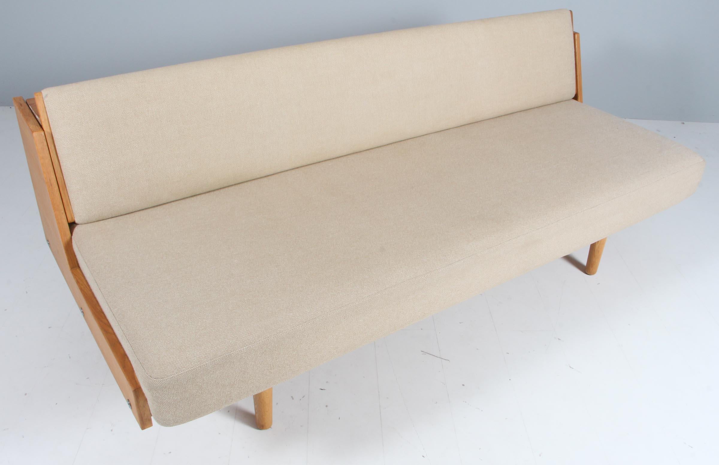 Designed by Hans Wegner for GETAMA this convertible daybed / sofa features a beautifully patinated oak frame and wool upholstery. The back reveals a hidden space for blankets, pillows etc. The model GE-258 was designed by Wegner in the early