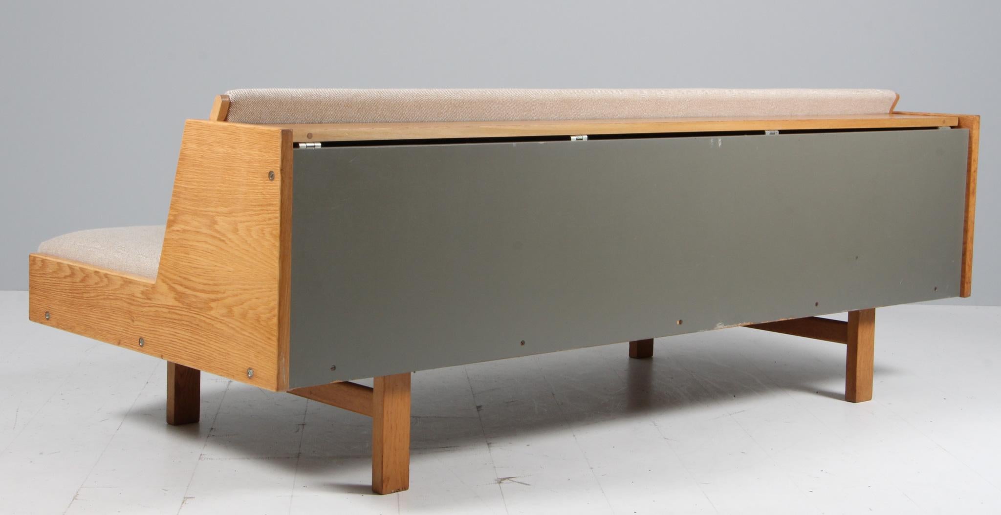 Disegnato da Hans Wegner per GETAMA, questo letto/divano convertibile presenta una splendida struttura in rovere patinato e un'imbottitura in lana. Il retro rivela uno spazio nascosto per coperte, cuscini, ecc. Il modello GE-268 è stato disegnato da
