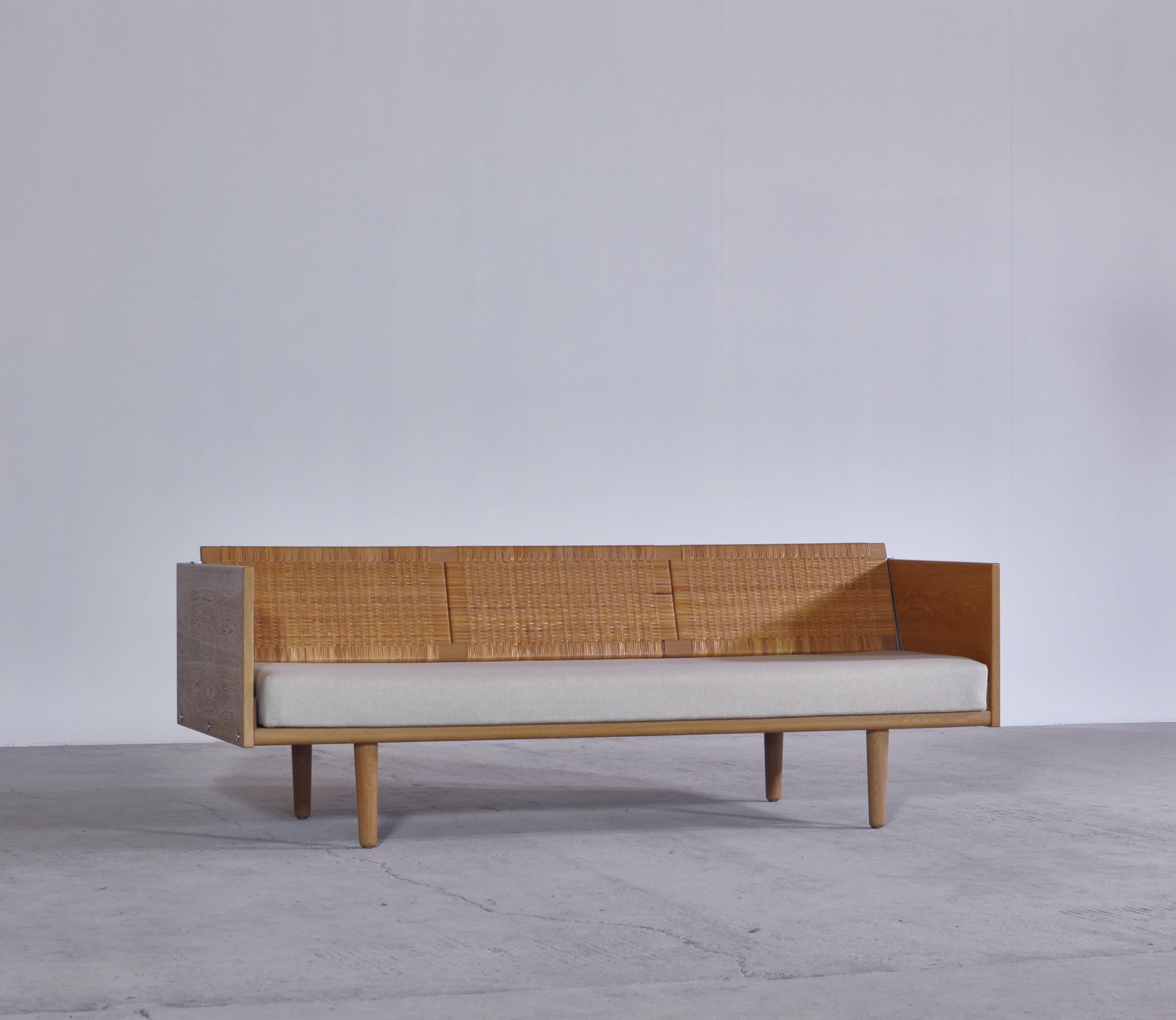 Designed by Hans Wegner for GETAMA this amazing convertible daybed / sofa features a beautifully patinated oak frame and woven cane / rattan back seat which reveals a hidden space for blankets, pillows etc. The model GE-7 was designed by Wegner in