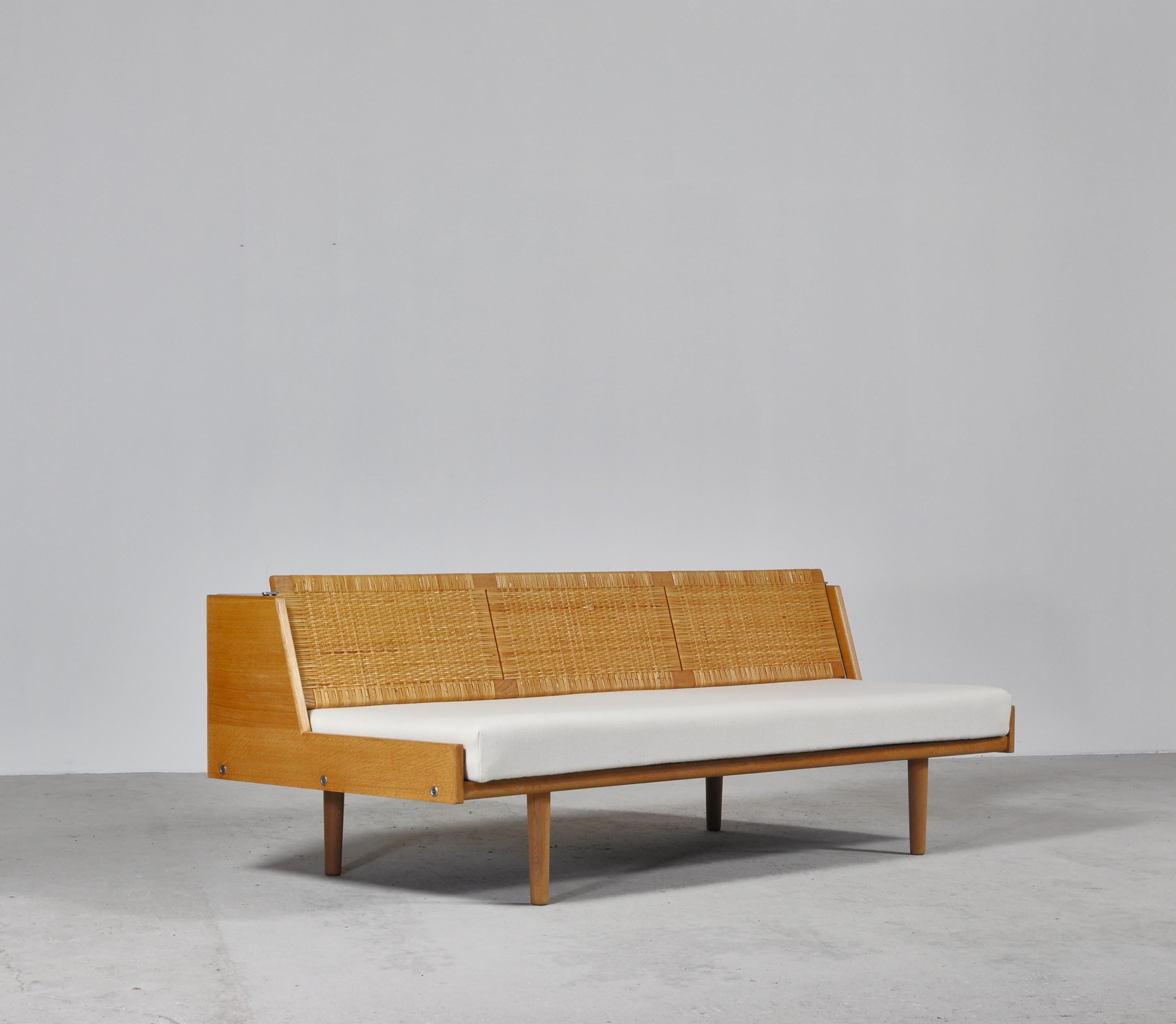 Designed by Hans Wegner for GETAMA this amazing convertible daybed / sofa features a beautifully patinated oak frame and woven cane / rattan back seat which reveals a hidden space for blankets, pillows etc. The model GE-7 was designed by Wegner in