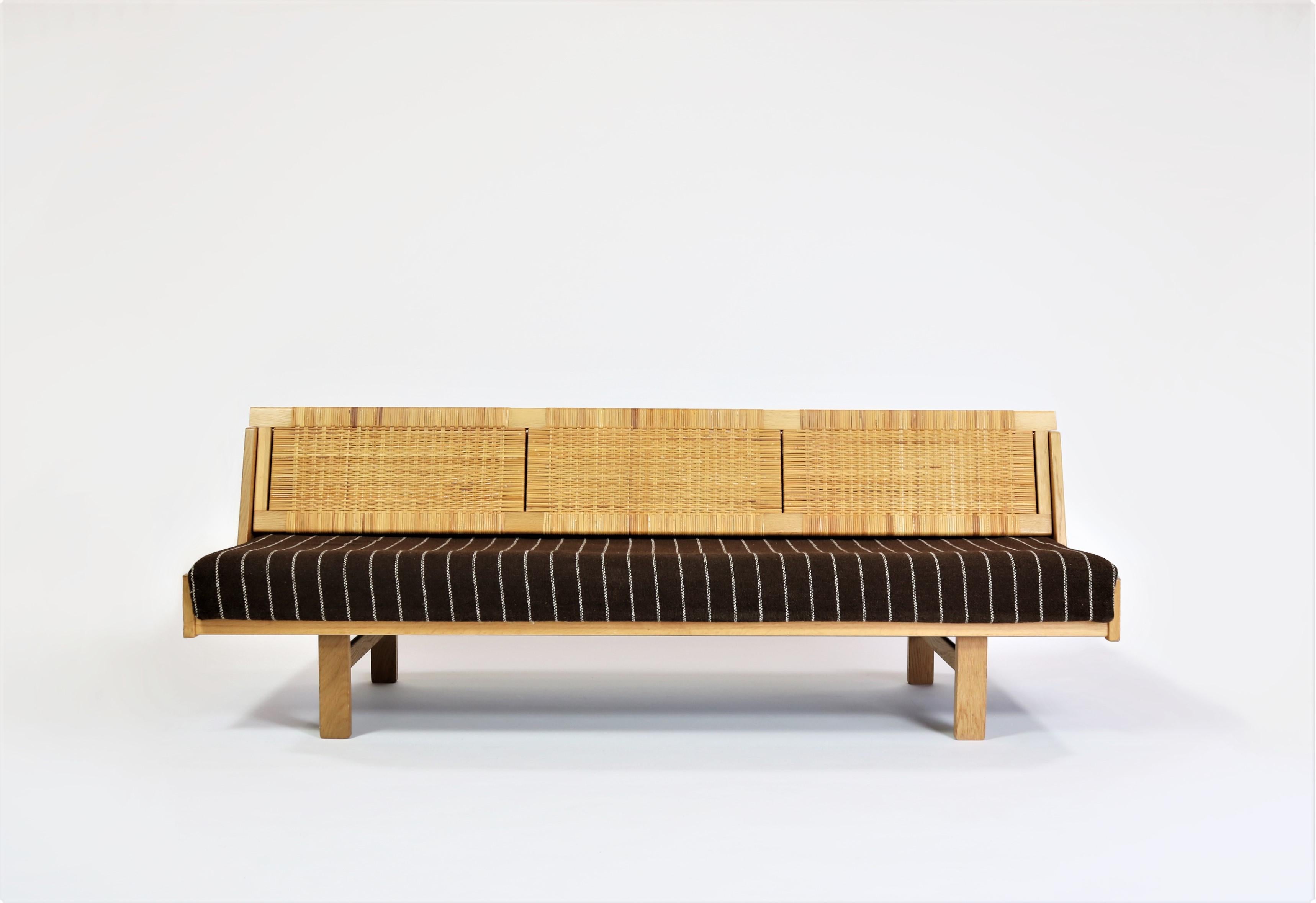 Designed by Hans Wegner for GETAMA this amazing convertible daybed / sofa features a beautifully patinated oak frame and woven cane / rattan back seat which reveals a hidden space for blankets, pillows etc. It also allows for more space to serve as