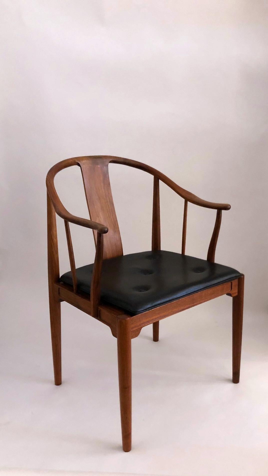 Hans J. Wegner:
 A walnut armchair “China chairs”. The China chair was designed by Hans J. Wegner in 1944.
Loose seat cushion upholstered with black leather, fitted with buttons. Model 4283. 
Manufactured 1977 by Fritz Hansen with maker's silver