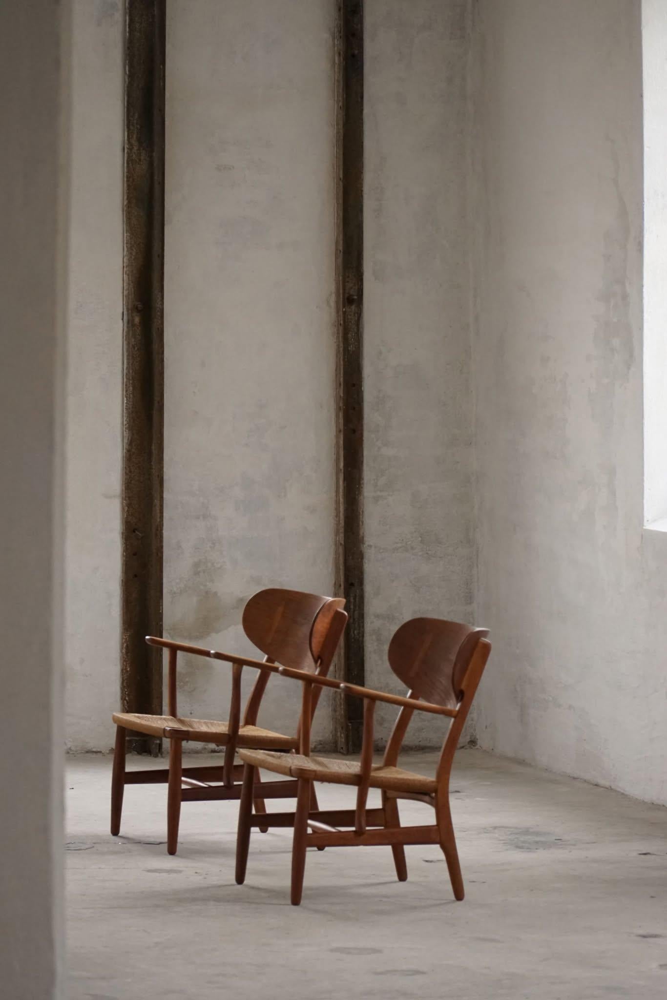Un impresionante par de Sillas de salón CH22 en roble con asientos de cuerda de papel tejida a mano, que ejemplifican la elegancia atemporal del diseño moderno danés. Diseñado por Hans J. Wegner para Carl Hansen & Søn en 1950. Este par en concreto