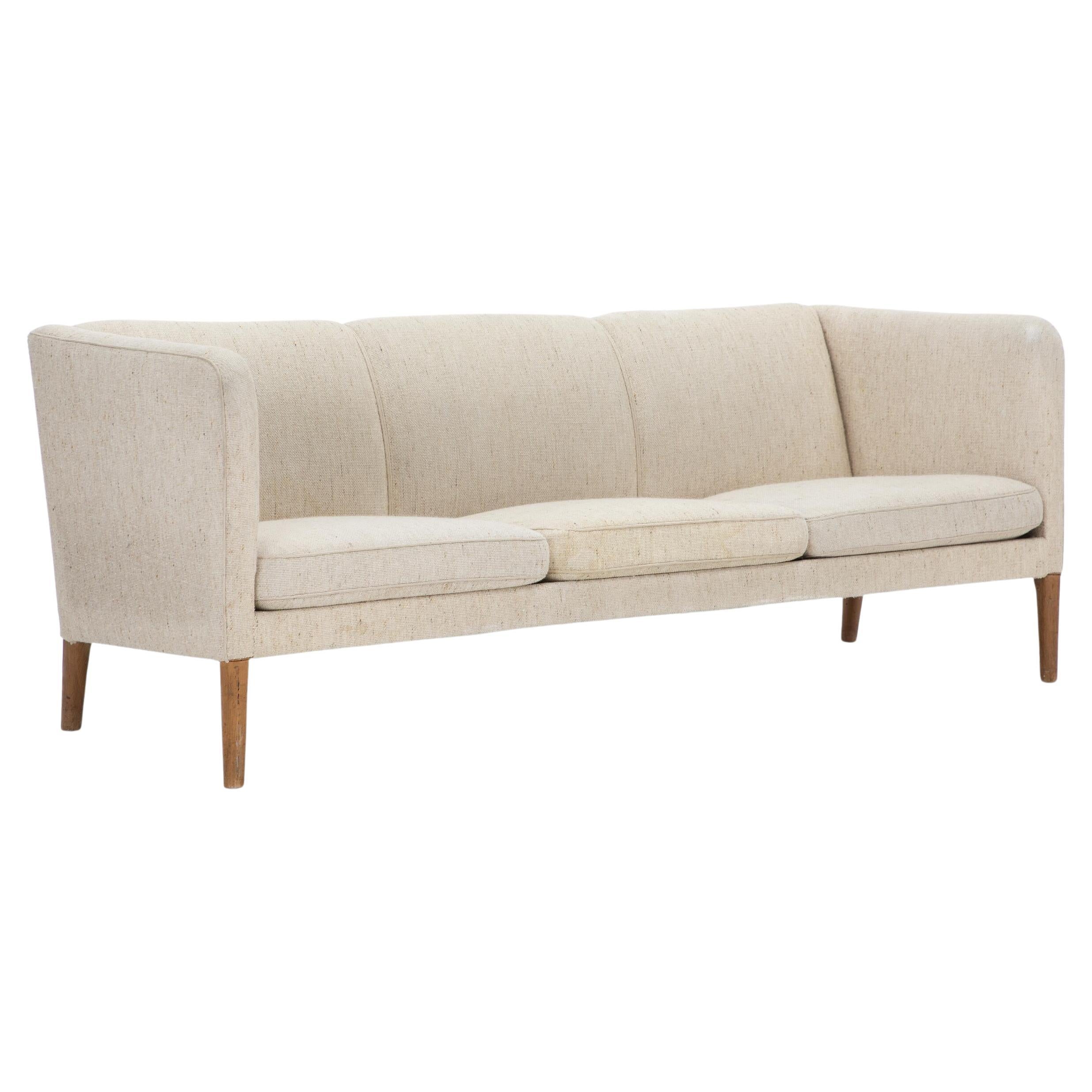 Hans J. Wegner: “AP 18”. Wool and oak three seater sofa. 

Manufactured by AP Stolen. 

Wear due to age and use, including scratches and marks on legs. Wool with stains, dirt and minor defects.
