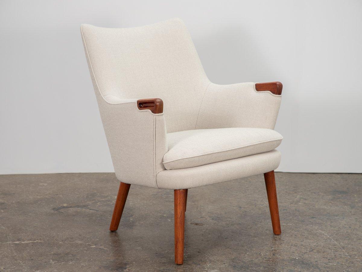 Paire de chaises rares, modèle AP-20, conçues par Hans J. Wegner, fabriquées par AP Stolen. La forme classique est accentuée par des poignées sculpturales en teck au niveau des accoudoirs. Notre paire a été fidèlement restaurée et tapissée en