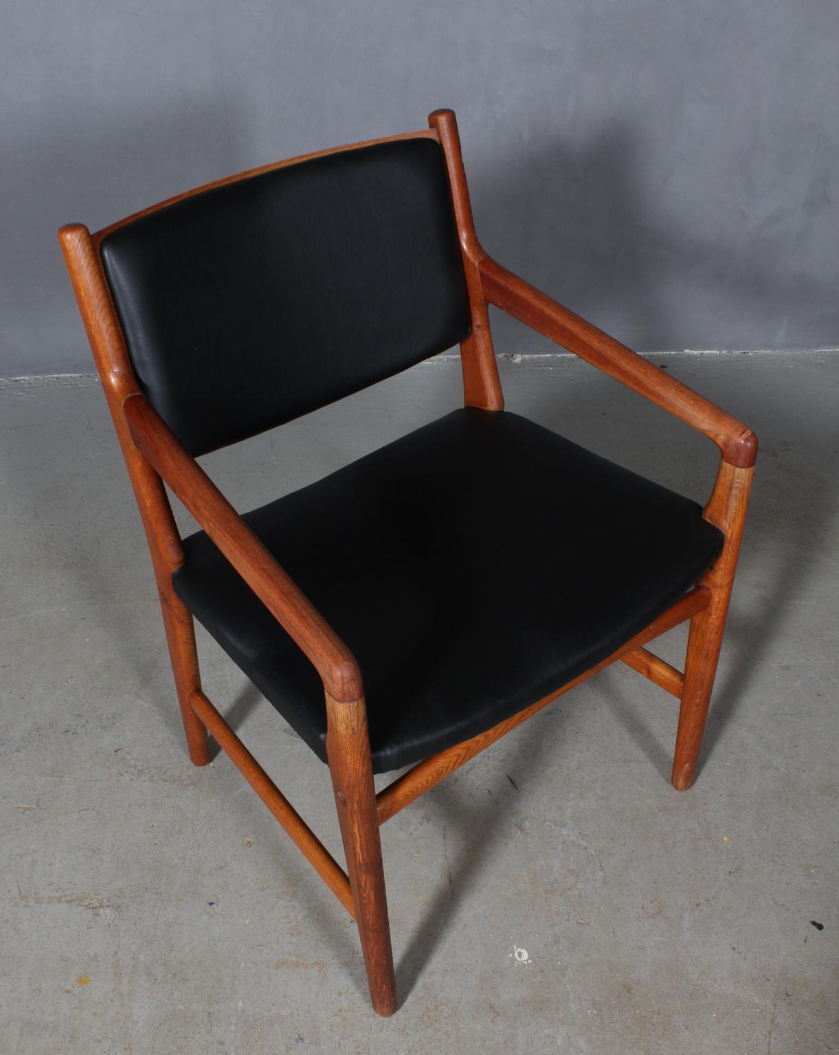 Hans J. Wegner armchair frame of oak and armrests of teak.

Seat and back new upholstered with black aniline leather.

Made by Johannes Hansen in the 1950s for Magasin Du Nords shoe department. Therefore there are holes in the chair for mounting