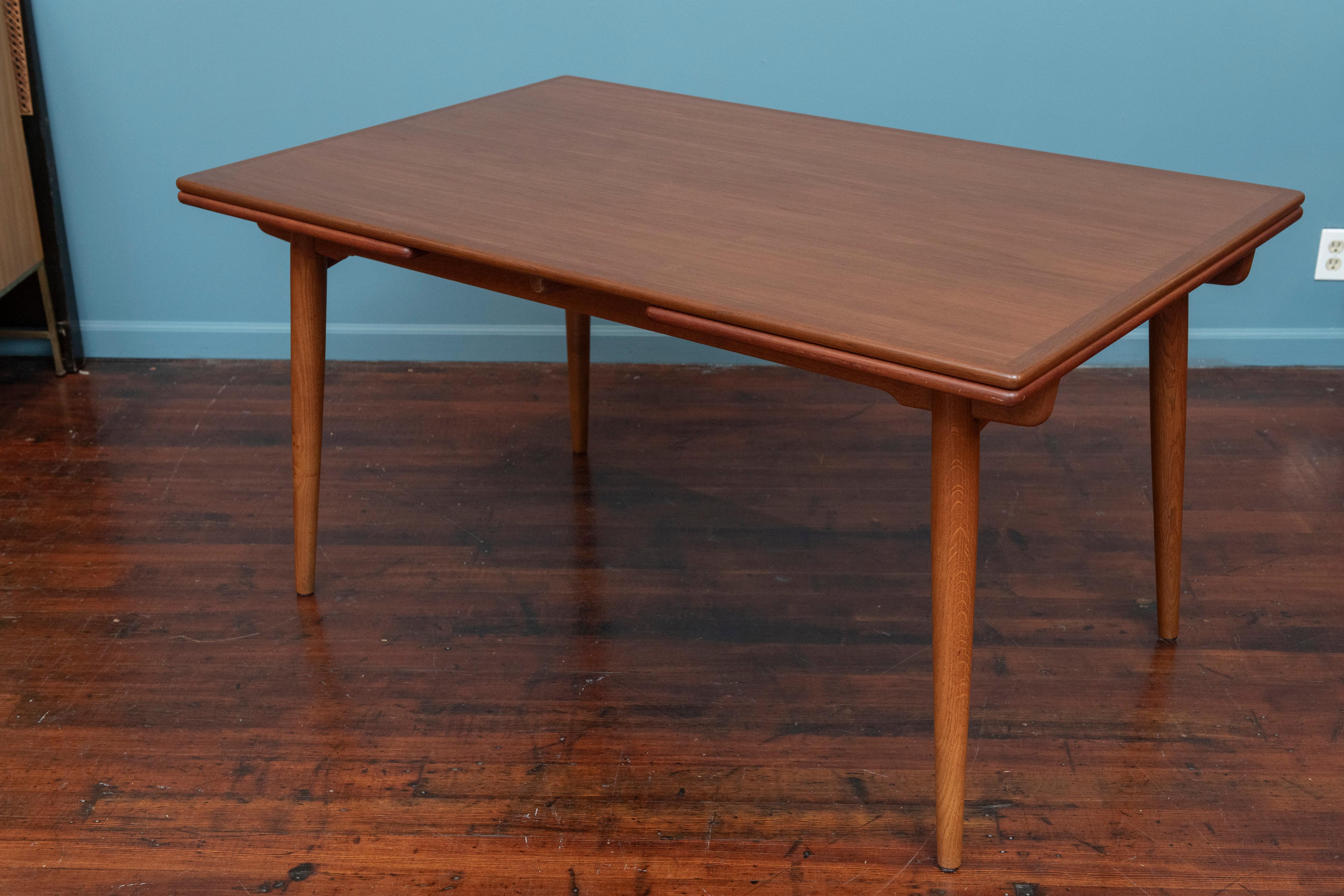 Hans J. Wegner design dining table Model AT-312 for Andreas Tuck. High quality materials and construction by the master of Danish cabinetry Hans Wegner. featuring a sculpted oak base a teak top and matching draw leaves.  The tables open and closes