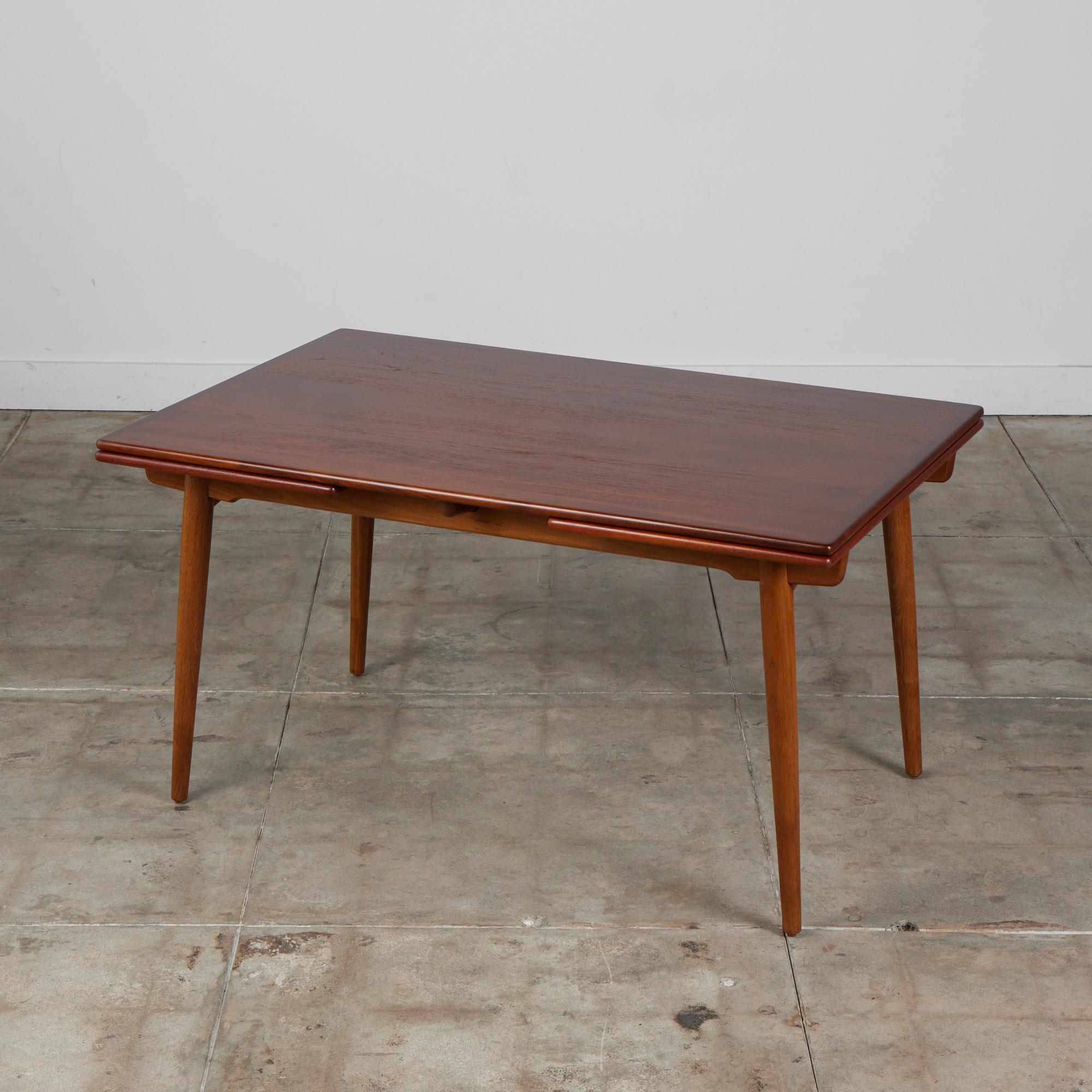 Teak top dining table by Hans J. Wegner for Andreas Tuck, c.1950s, Denmark.
This rectangular teak table features two leaves that extend from underneath the table to increase the tables length in 94 inches when fully extended. The table top sits