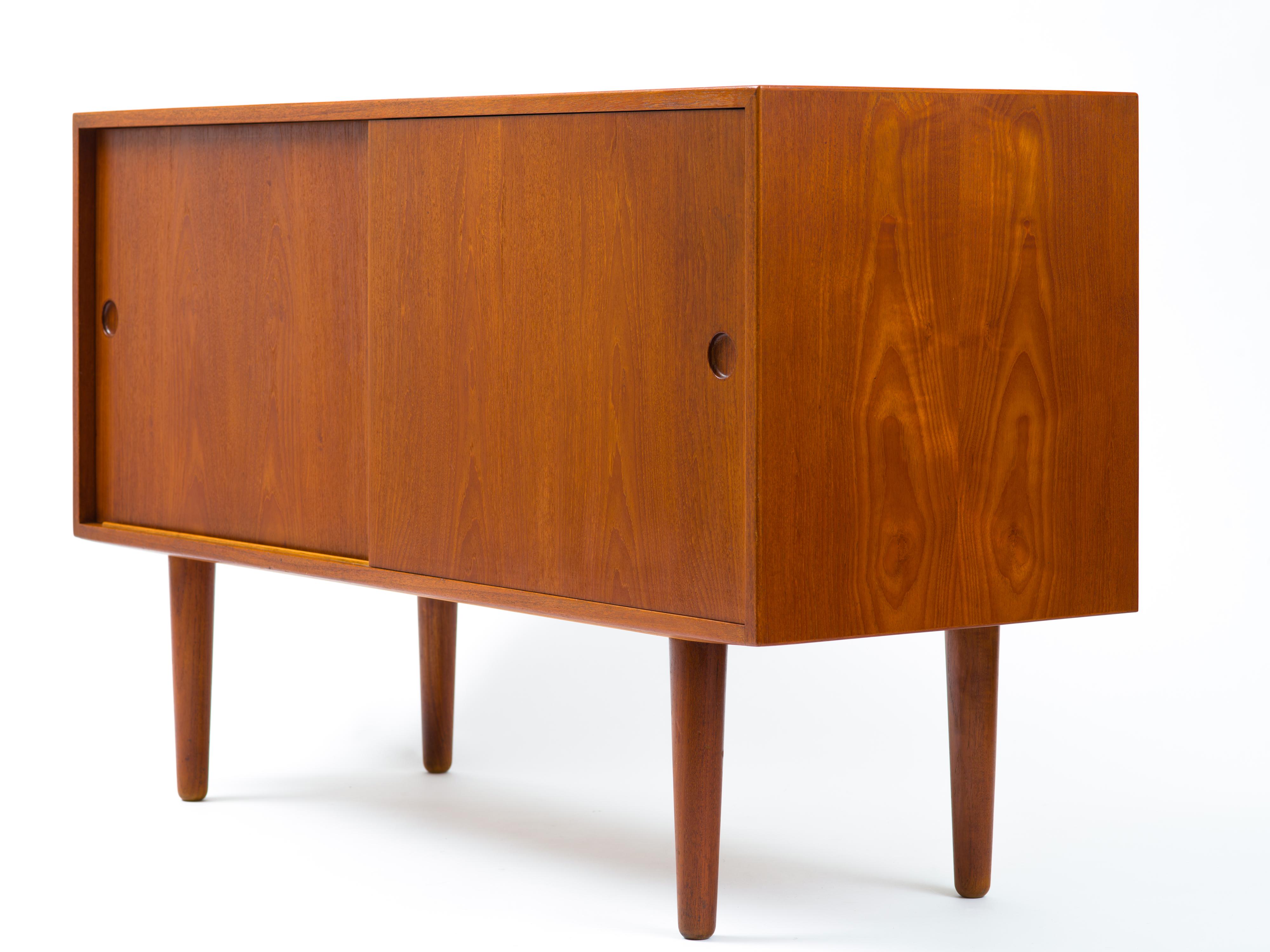 Fine and rare sideboard designed by Hans Wegner and built by eminent Danish cabinetmaker, Johannes Hansen. A pair of doors with integrated pulls conceals two adjustable shelves to the left and five adjustable drawers to the right. The case bears