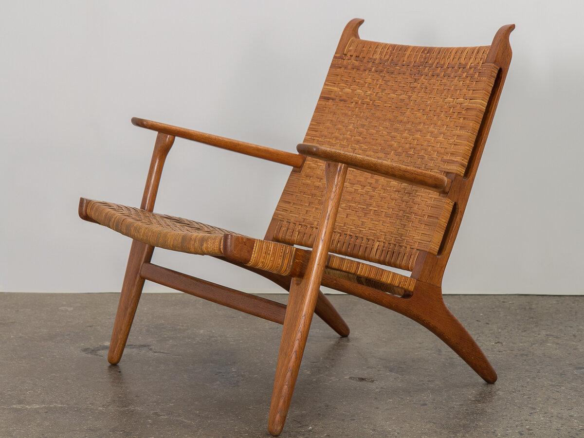 Early CH-27 lounge chair, designed by Hans J. Wegner for Carl Hansen. Constructed from solid oak, the reclining open frame features beautiful sculptural details at the back rest. Wide and sturdy armrests enhance the comfort level. The original