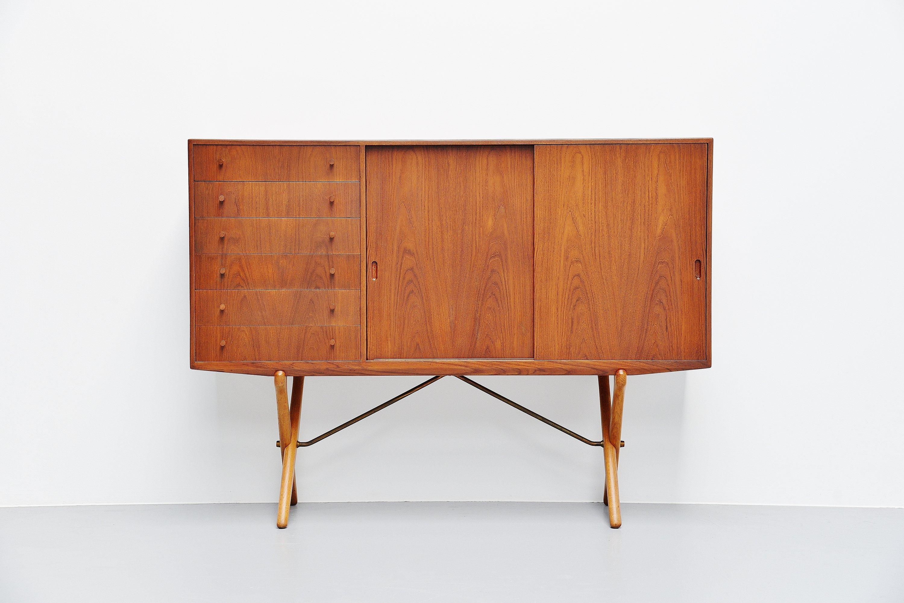 Fantastic high cabinet model CH-304 designed by Hans J. Wegner and manufactured by Carl Hansen & son, Denmark, 1953. The cabinet has solid oak legs connected with brass bars, the cabinet is made of teak veneer and is fully refinished. The left past