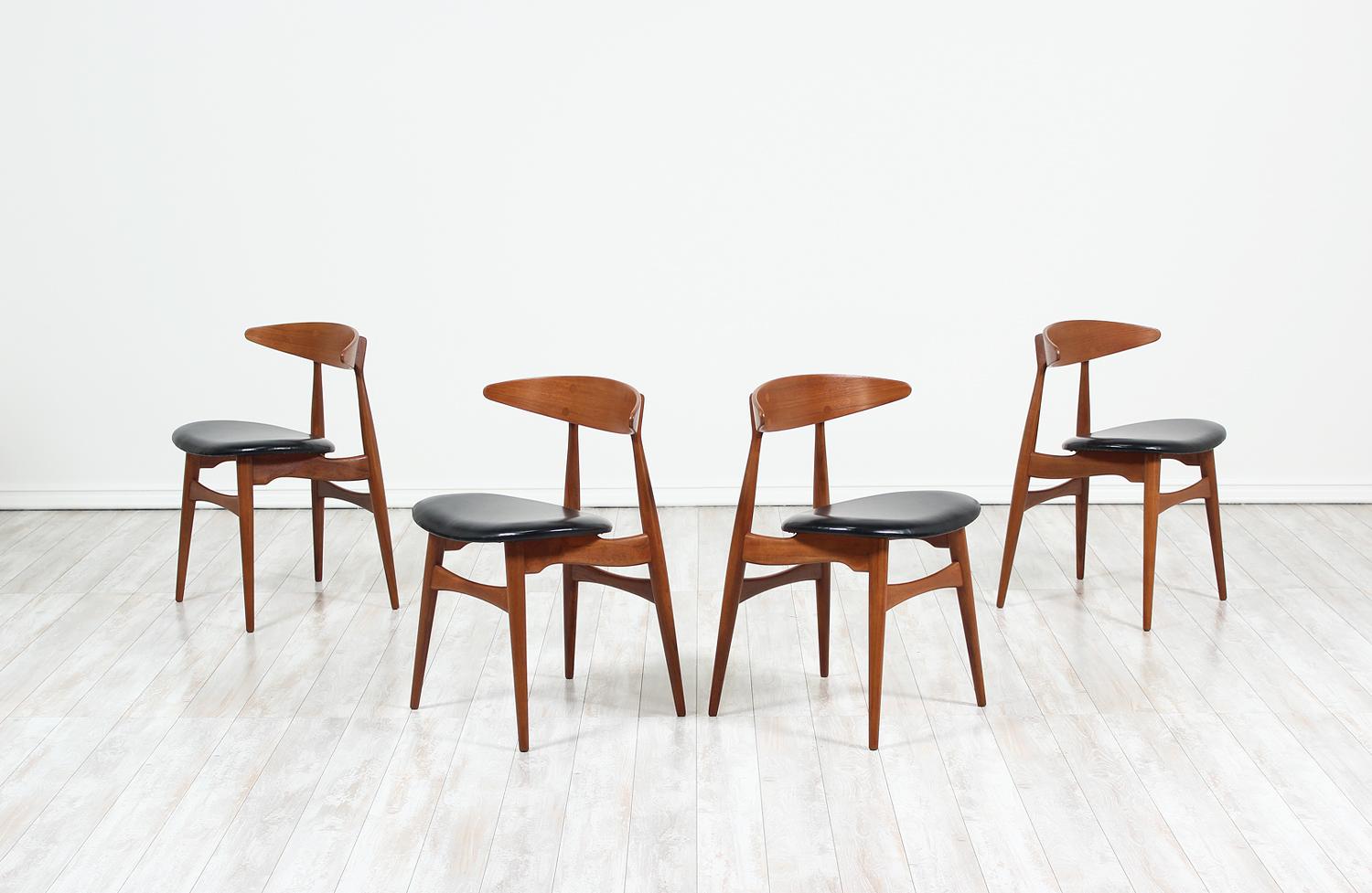 Set of four iconic CH-33 dining chairs designed by Hans J. Wegner for Carl Hansen & Søn in Denmark in 1957. An intricate design that features a uniquely structured seat that appears to float above the inclined, tapered legs and a shell back rest
