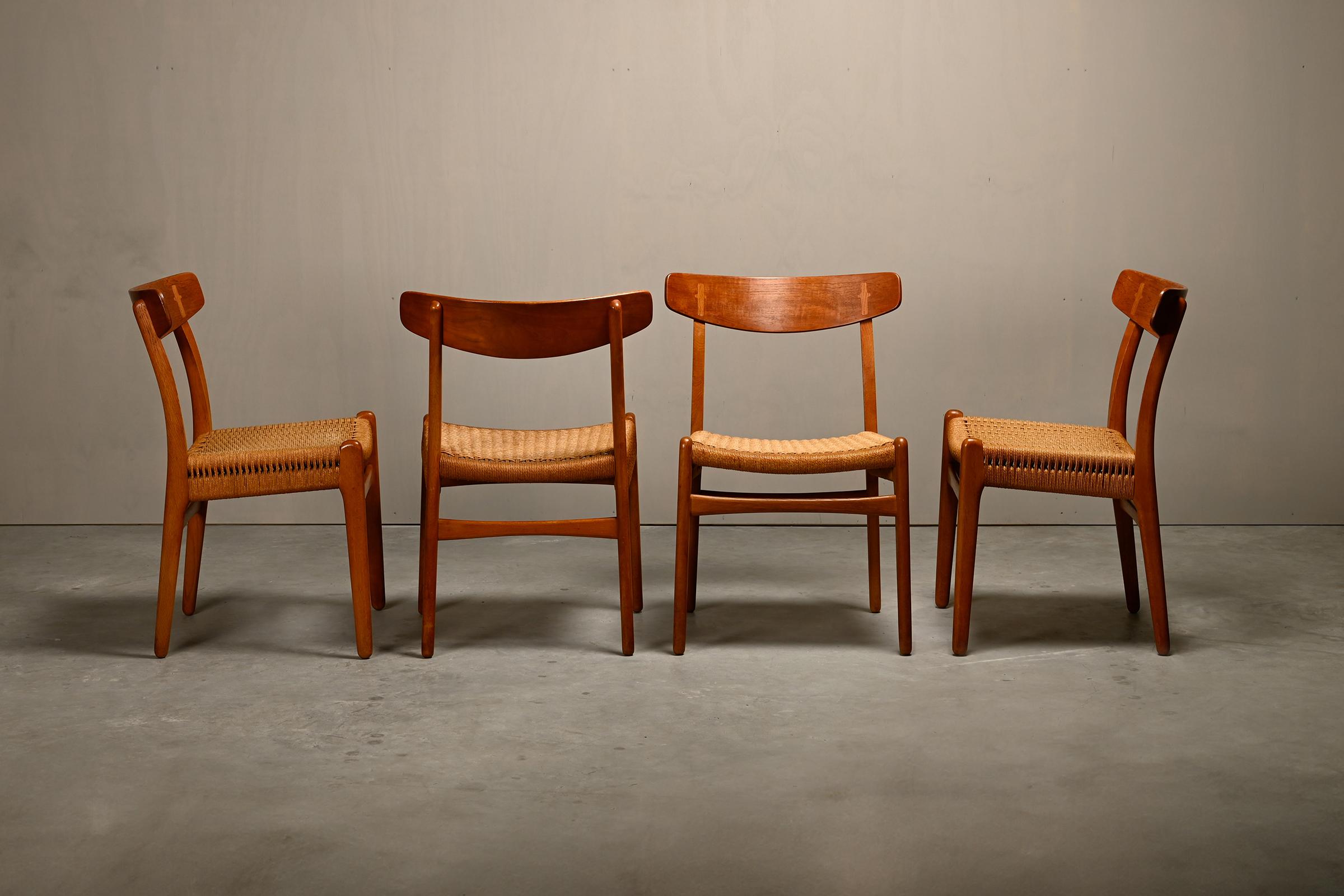Early set of four CH23 dining chairs designed by Hans J. Wegner for Carl Hansen & Søn, Denmark 1950s. Beautifully and warm aged Oak frames with teak backrests and hand woven papercord seats. Very good original vintage condition with slight traces of